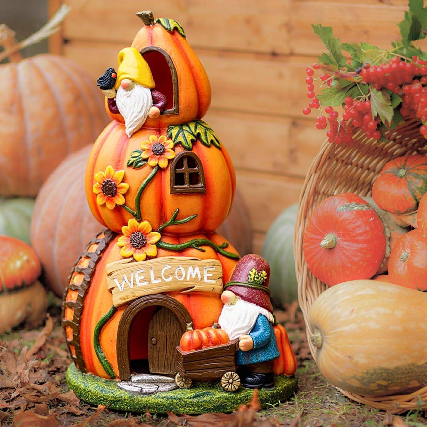 Eine Gartenzwergfigur, die einen Kürbis hält, steht neben einem kürbisförmigen Haus mit der Aufschrift 