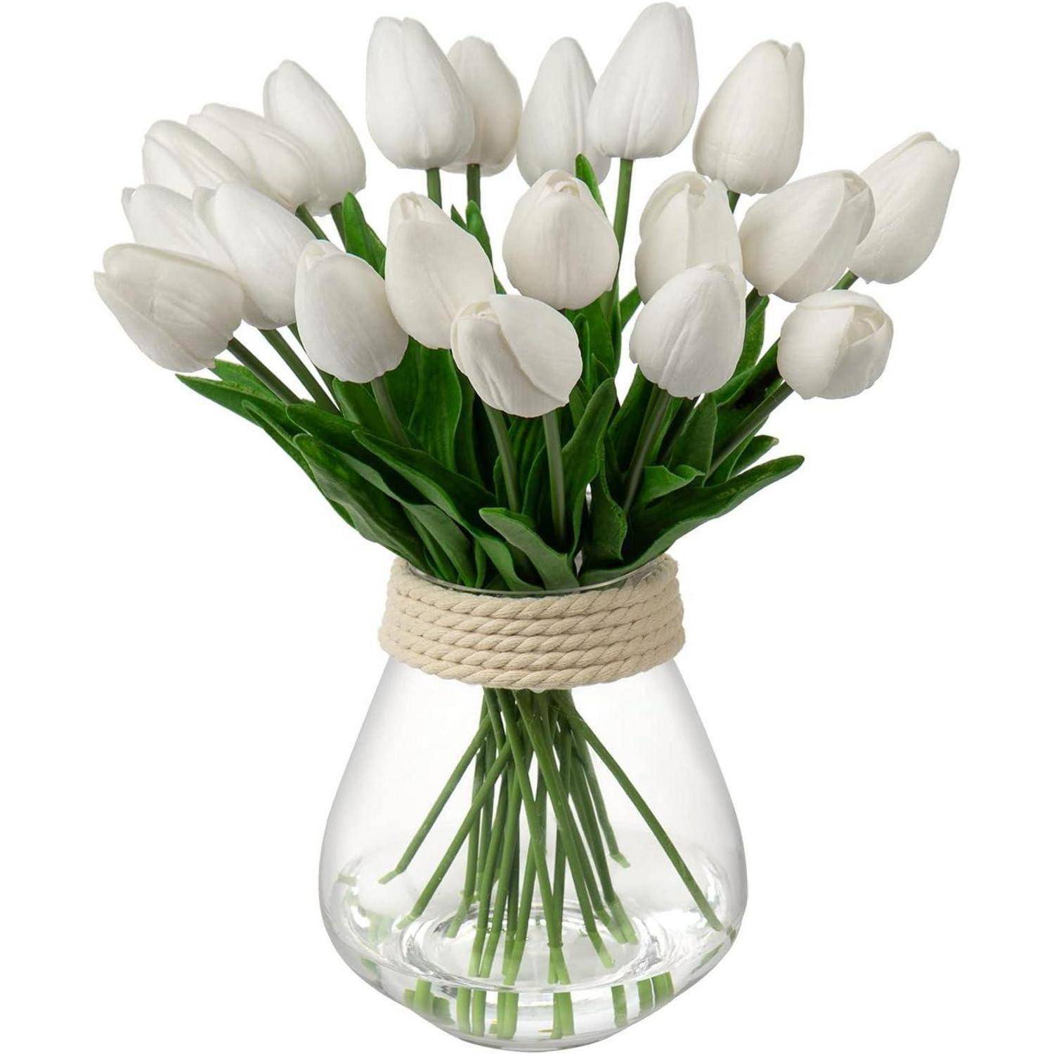 Eine klare Vase hält einen Blumenstrauß aus weißen Tulpen mit grünen Blättern. Die Stiele sind mit einem Seil nahe dem oberen Rand der Vase zusammengebunden.
