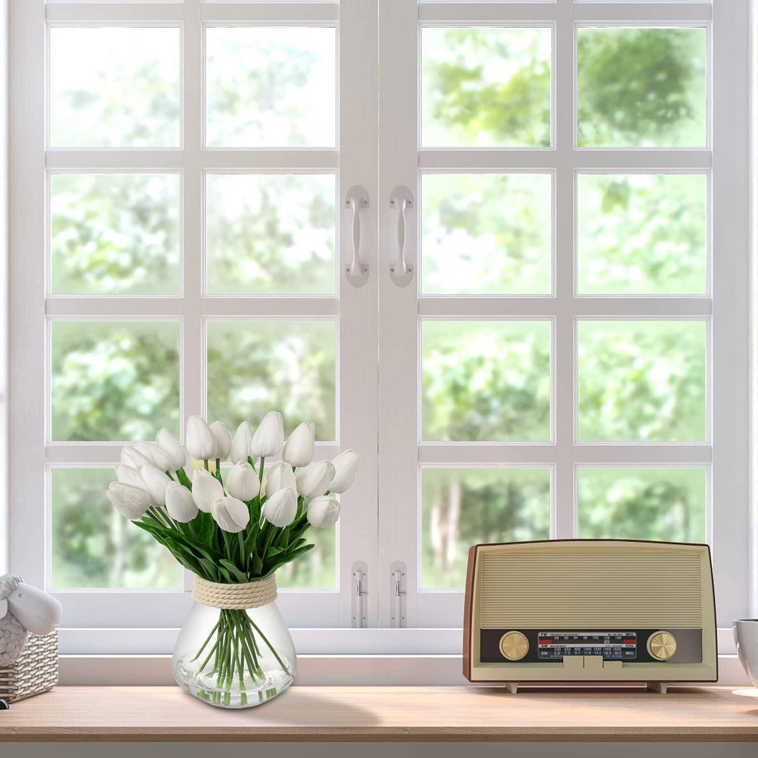 Ein Fenster mit einer Vase weißer Tulpen und einem Vintage-Radio auf dem Fensterbrett. Grünzeug und Sonnenlicht sind draußen zu sehen.