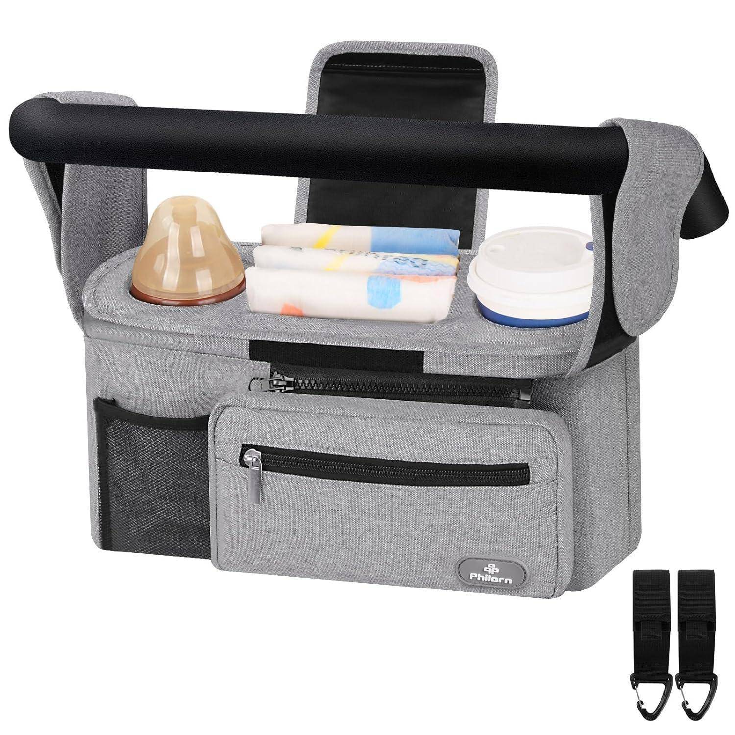 Ein grauer Kinderwagen-Organizer mit mehreren Taschen hält eine Babyflasche, Feuchttücher und Schnuller. Inklusive abnehmbarem Schultergurt.