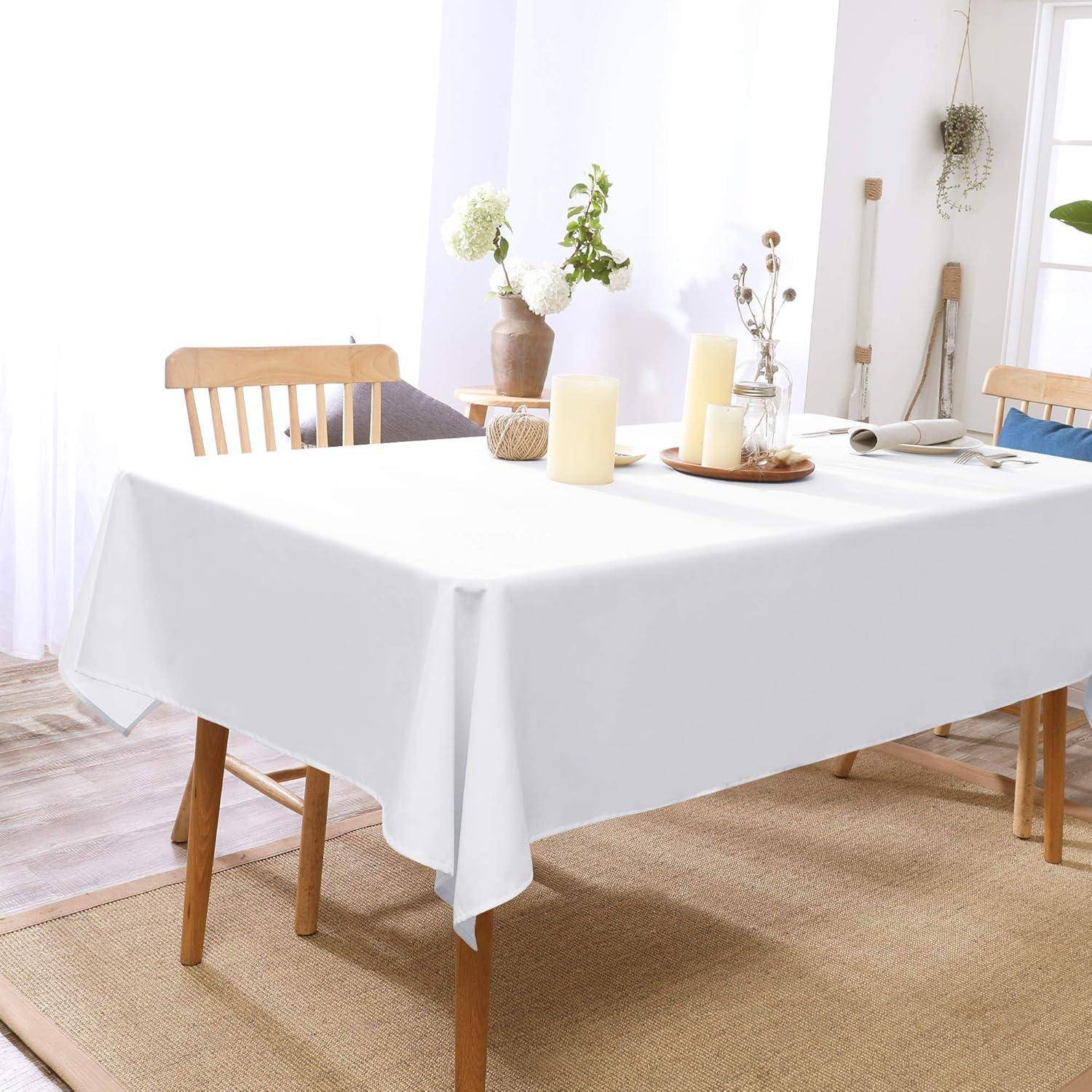 Ein Esszimmerensemble mit einer weißen Tischdecke, die auf einem Tisch ausgebreitet ist und von Holzstühlen umgeben wird. Dekorative Vasen mit Blumen stehen auf dem Tisch.