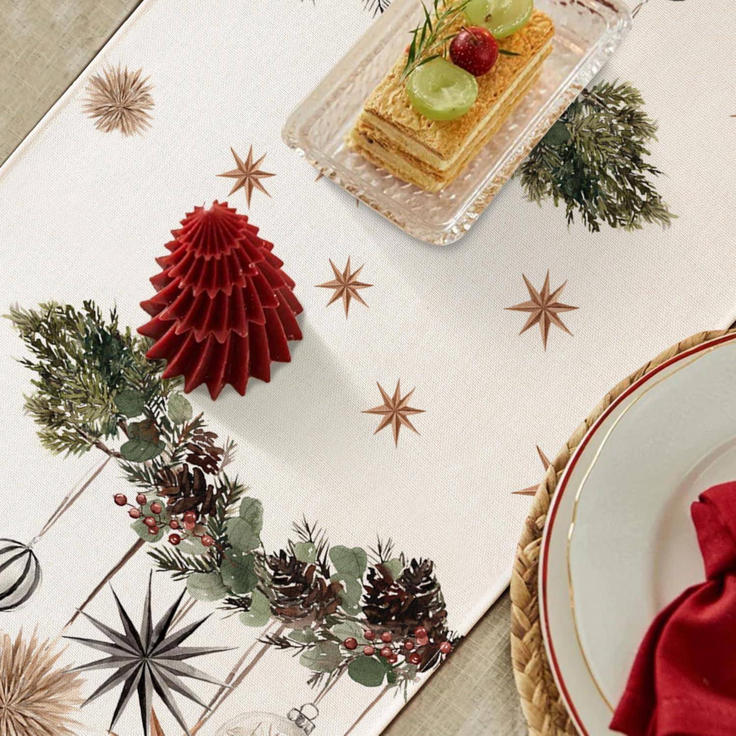 Ein festlicher Tisch mit einer dekorativen Decke, die Tannenzweige und Sterne zeigt, eine Kuchenscheibe auf einem Glasteller und eine rot gefaltete Serviette auf einem Teller.