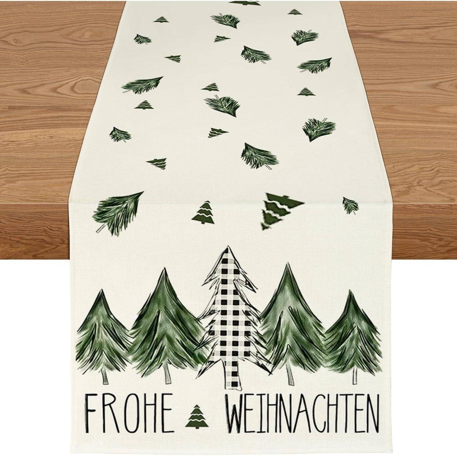 Ein weißer Tischläufer mit grünen Baumillustrationen und deutschem Text ‚Frohe Weihnachten' am unteren Rand.