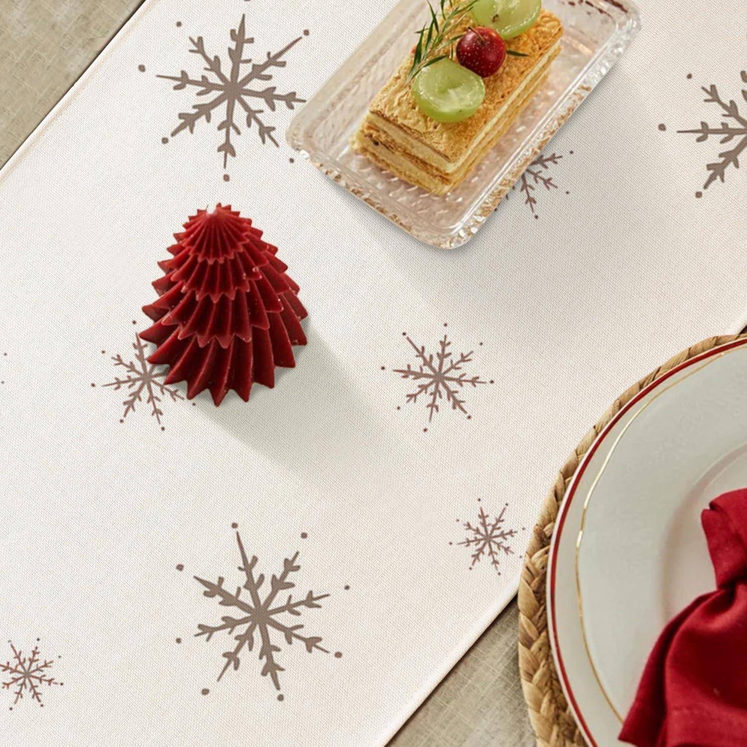 Ein festlich gedeckter Tisch mit einer roten Papiergirlande und einem verzierten Dessert auf einer Schneeflocken-gemusterten Tischdecke, neben einem gedeckten Teller.