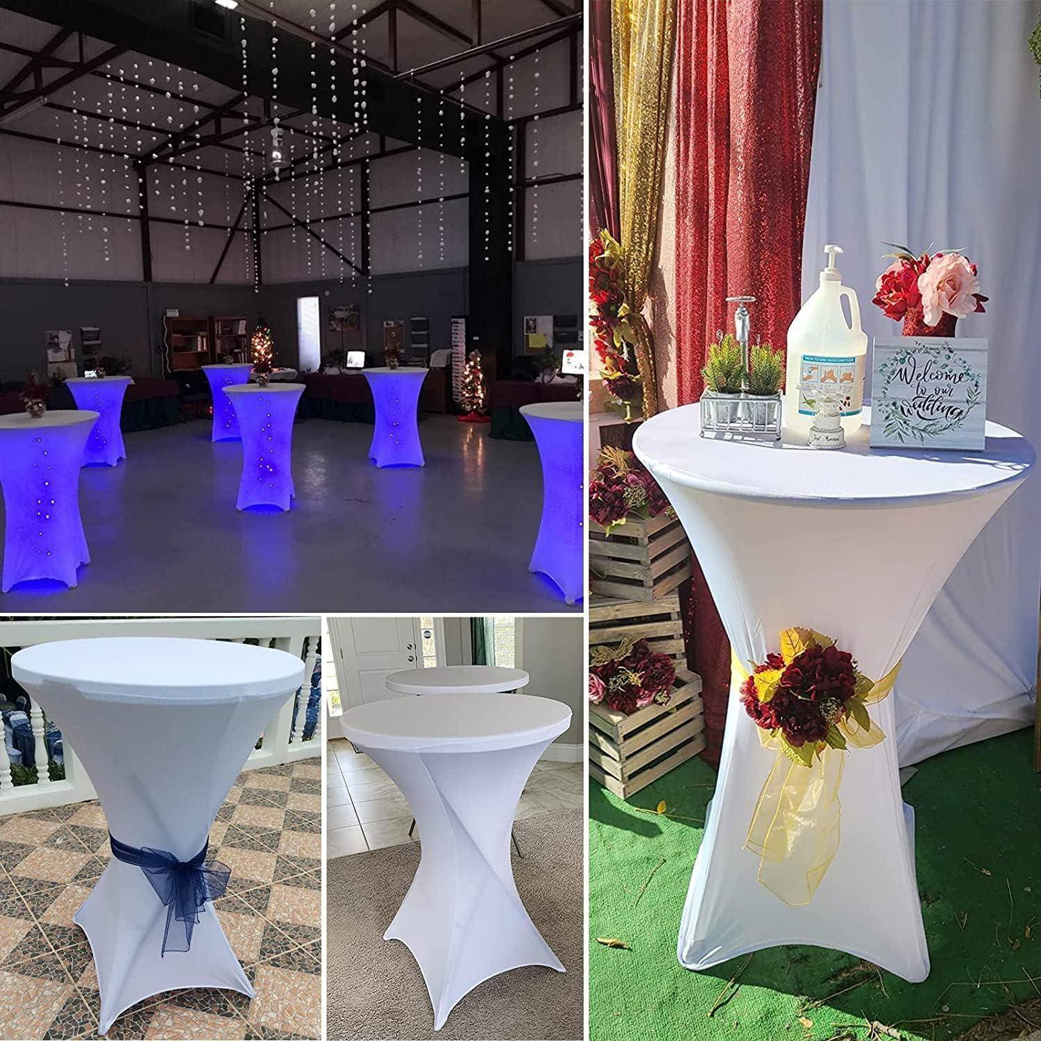 Veranstaltungsraum mit beleuchteten Cocktailtischen, einige mit Blumen und Bändern dekoriert. Ein Tisch zeigt Handdesinfektionsmittel und Blumen.