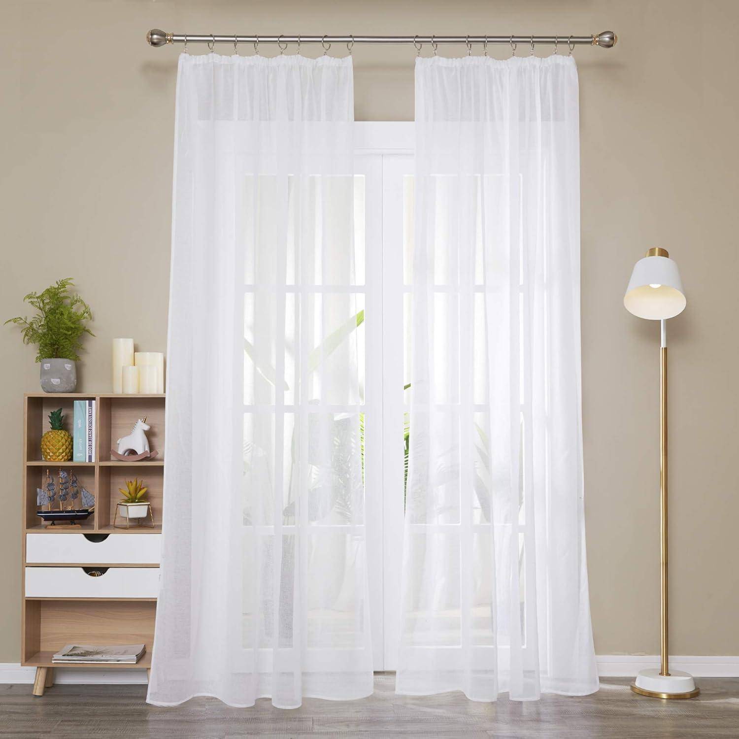 Weiße transparente Vorhänge am Fenster durchfluten den Raum mit natürlichem Licht. Ein kleines Holzregal mit Deko und eine hohe weiße Lampe befinden sich in der Nähe.