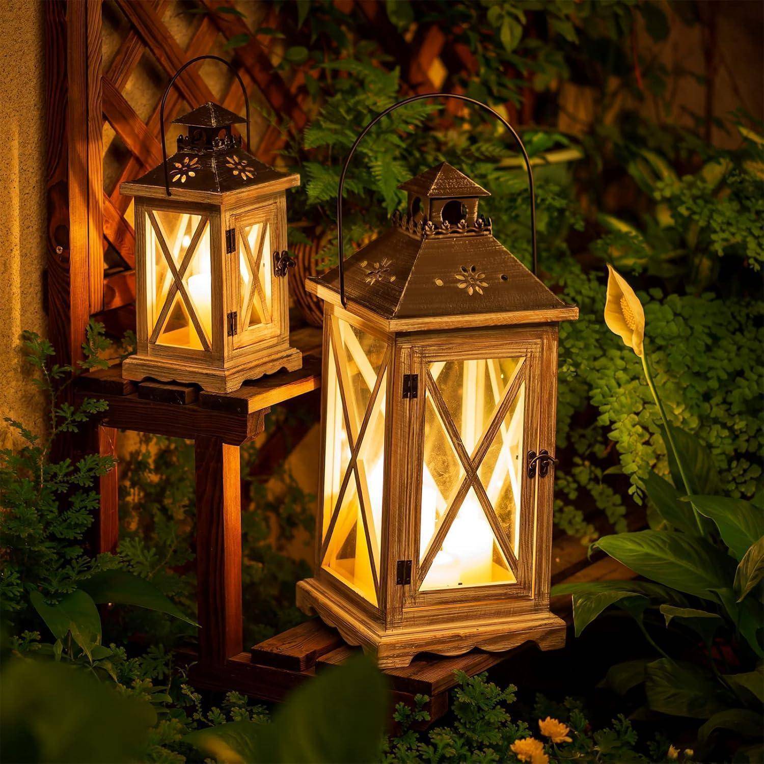 Zwei hölzerne Laternen mit leuchtenden Kerzen erhellen einen Garten bei Nacht, umgeben von üppigen grünen Pflanzen und einem hölzernen Rankgitterhintergrund.