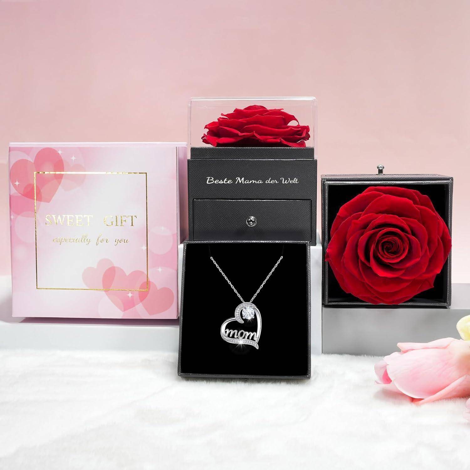 Ein 'Sweet Gift'-Set mit einer konservierten roten Rose in einer durchsichtigen Box und einer 'Mama' Anhängerkette in einer schwarzen Box, platziert auf einer weißen Oberfläche.