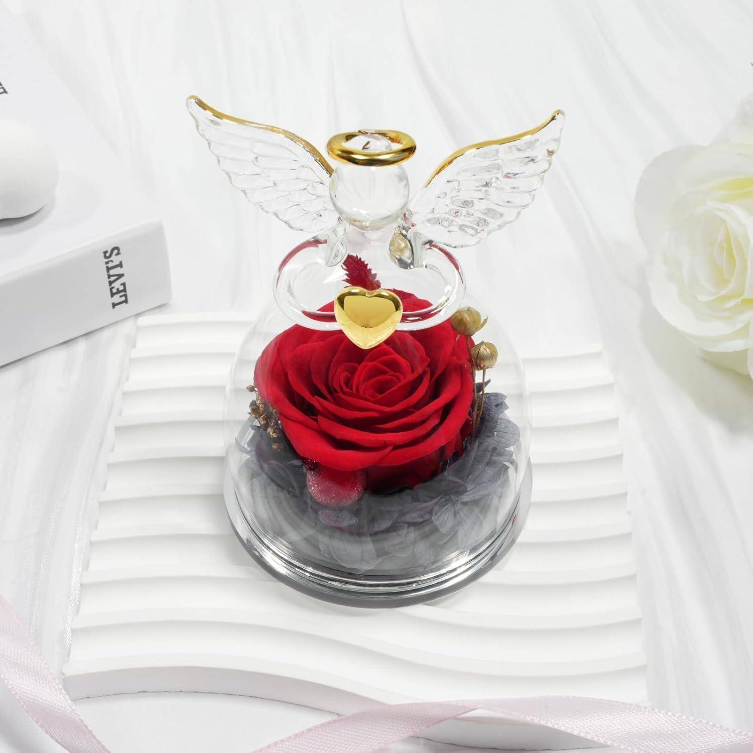 Glasflügelornament mit einer konservierten roten Rose im Inneren, das auf einer strukturierten weißen Oberfläche sitzt und einen eleganten dekorativen Akzent setzt.