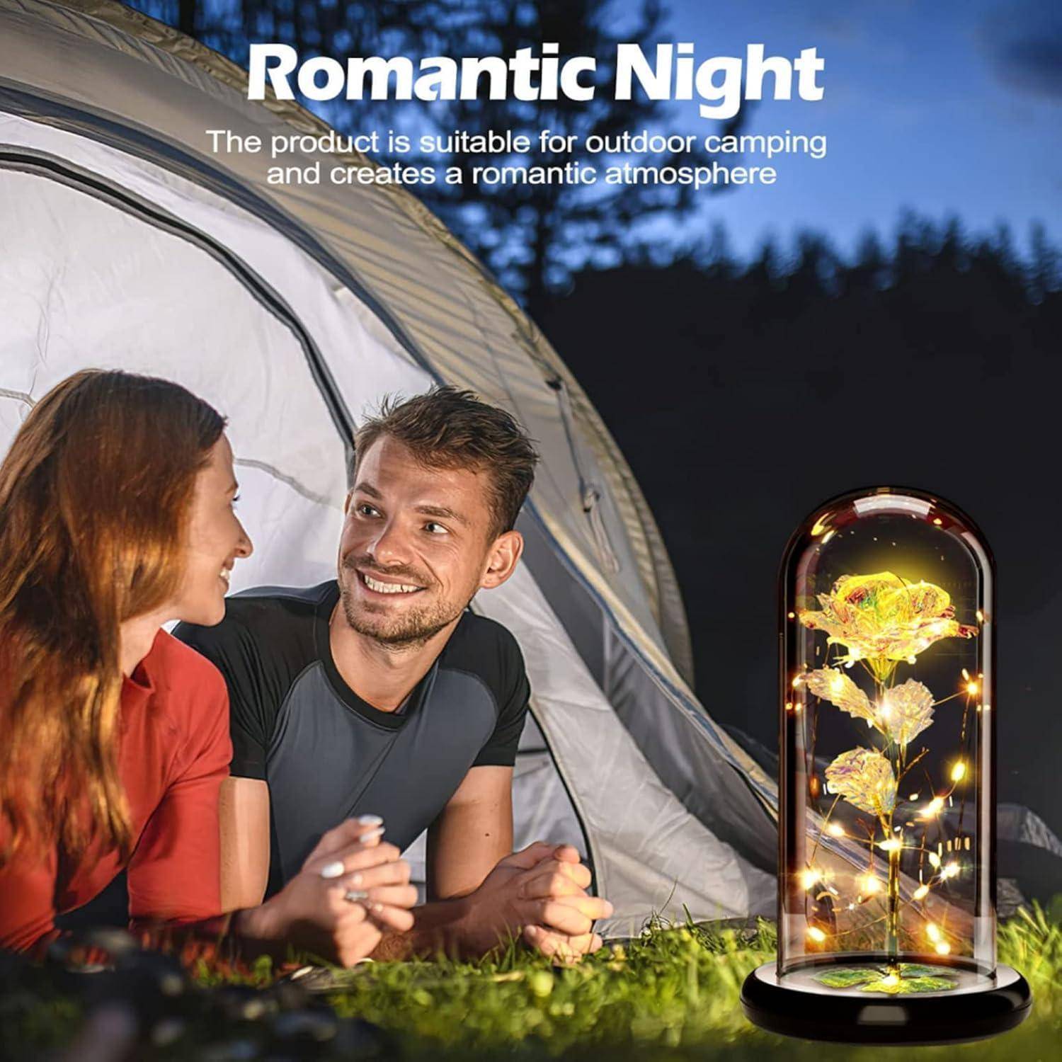 Ein Paar lächelt sich nachts außerhalb eines Zeltes an, neben einer beleuchteten Blumenausstellung. Text liest sich „Romantische Nacht