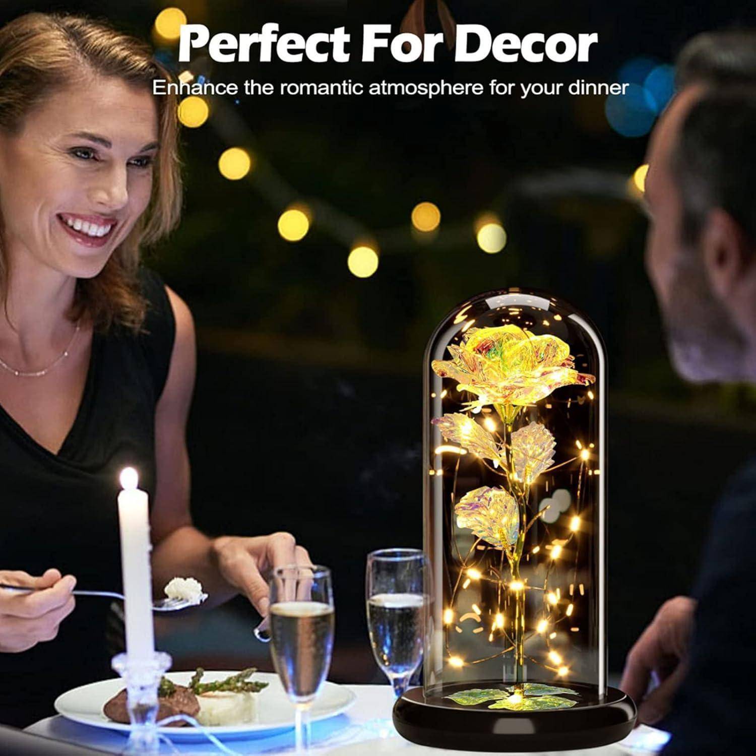 Eine Frau und ein Mann genießen ein Dinner an einem kerzenbeleuchteten Tisch. Eine beleuchtete Blumendekoration unter einer Glasglocke verstärkt die romantische Atmosphäre.
