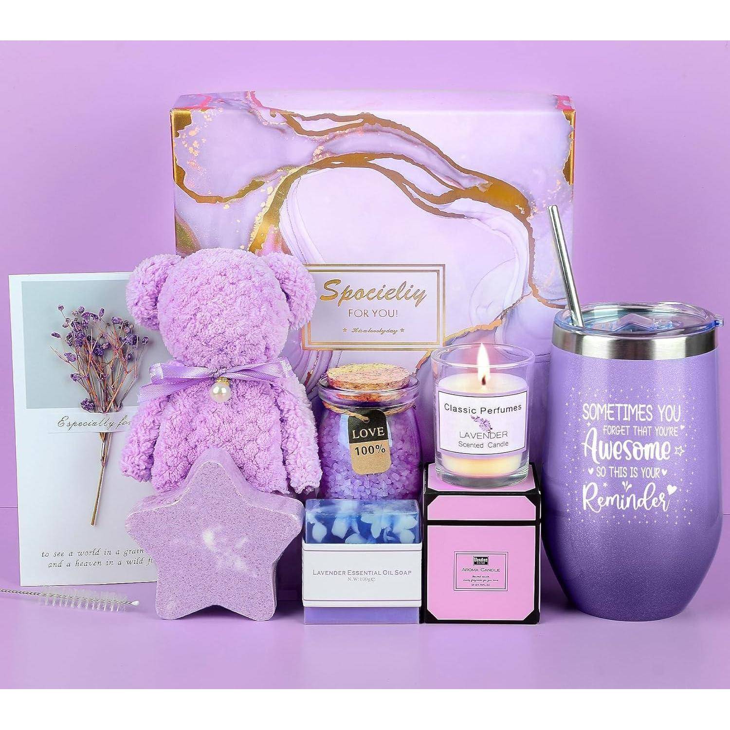 Geschenkset bestehend aus einer Karte, einem Lavendelbären, einer Kerze, einem Parfüm, einer Tasse mit Zitat, einem Strohhalm, einem Blütenzweig und einer sternenförmigen Seife, alles in Lavendeltönen.