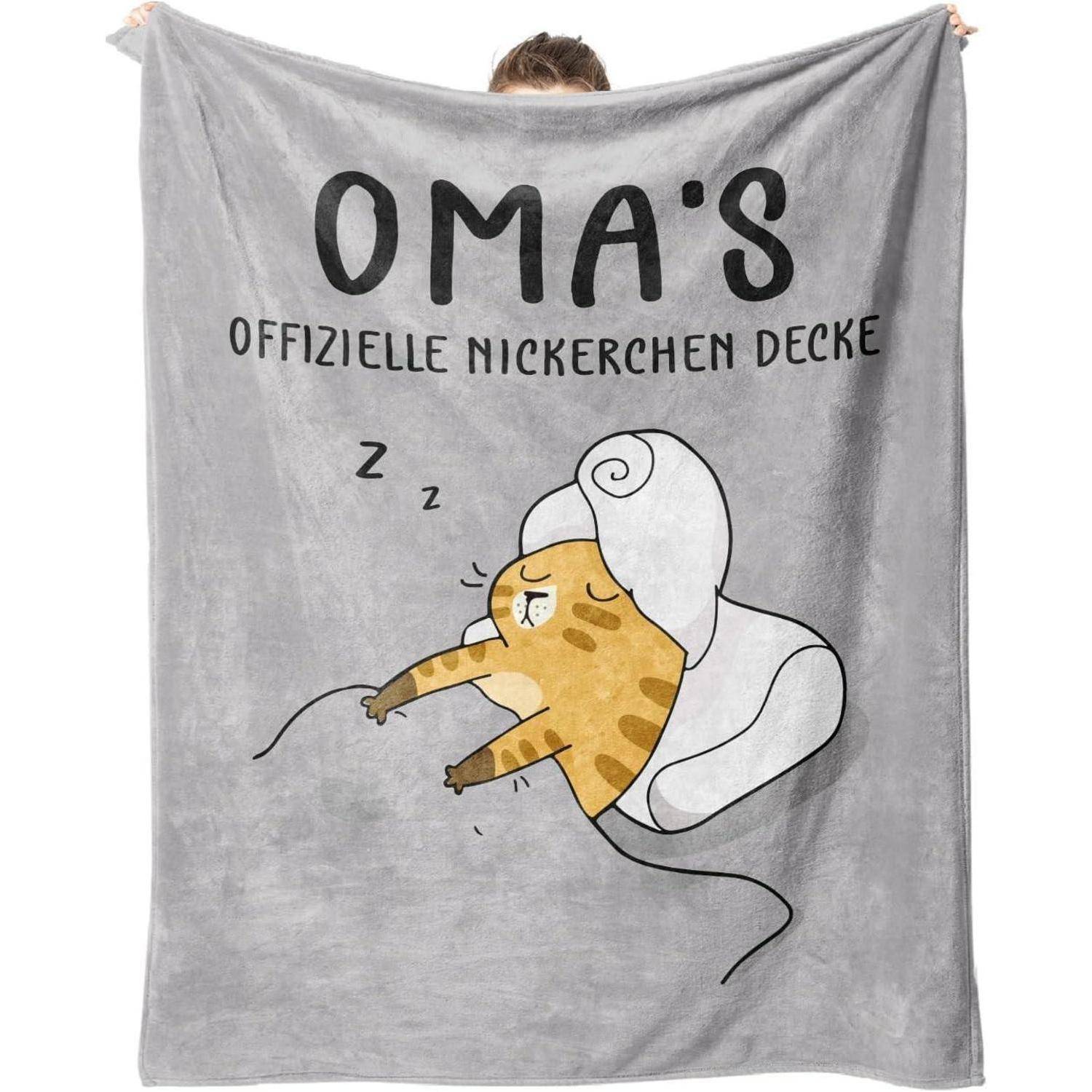 Eine Person hält eine graue Decke mit einer Illustration einer schlafenden Katze in Lockenwicklern, betitelt 