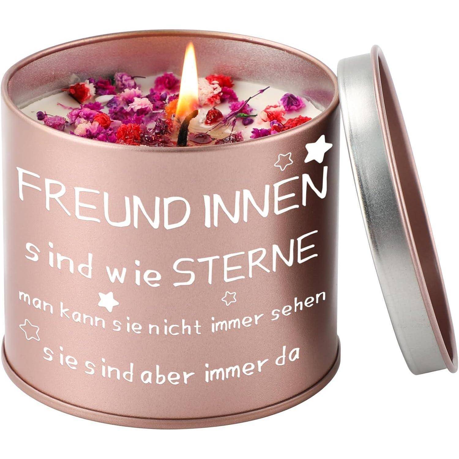 Eine brennende Kerze in einer rosa Dose mit dem Text 'FREUNDINNEN sind wie STERNE man kann sie nicht immer sehen sie sind aber immer da'. Dekoriert mit getrockneten Blumen.