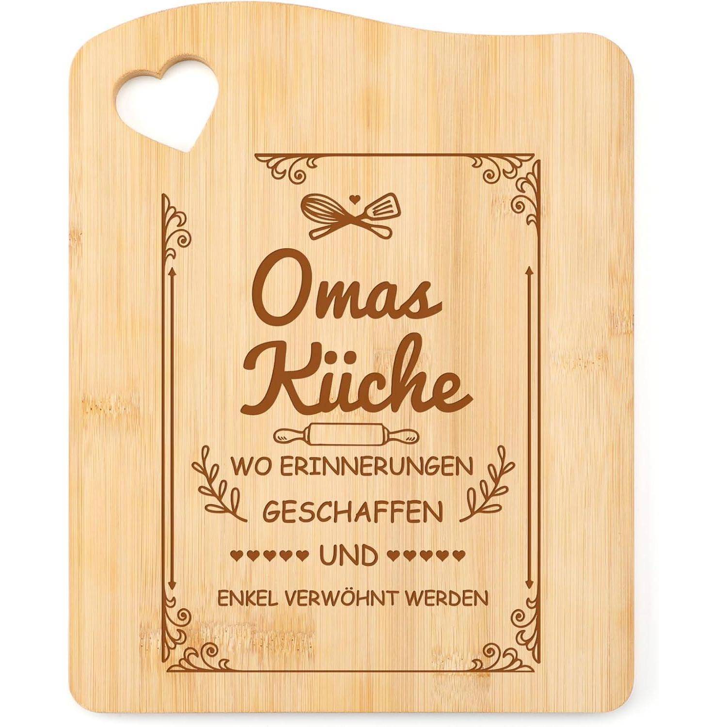 Ein Holzschneidebrett mit Herzausschnitt, graviert mit dem Text 'Omas Küche - wo Erinnerungen geschaffen und Enkel verwöhnt werden', umgeben von dekorativen Elementen.