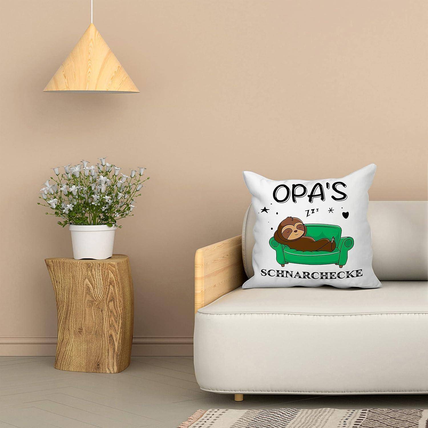 Ein gemütliches Zimmer mit einem weißen Sofa, das ein Kissen mit einer schlafenden Faultier-Illustration und dem Text 