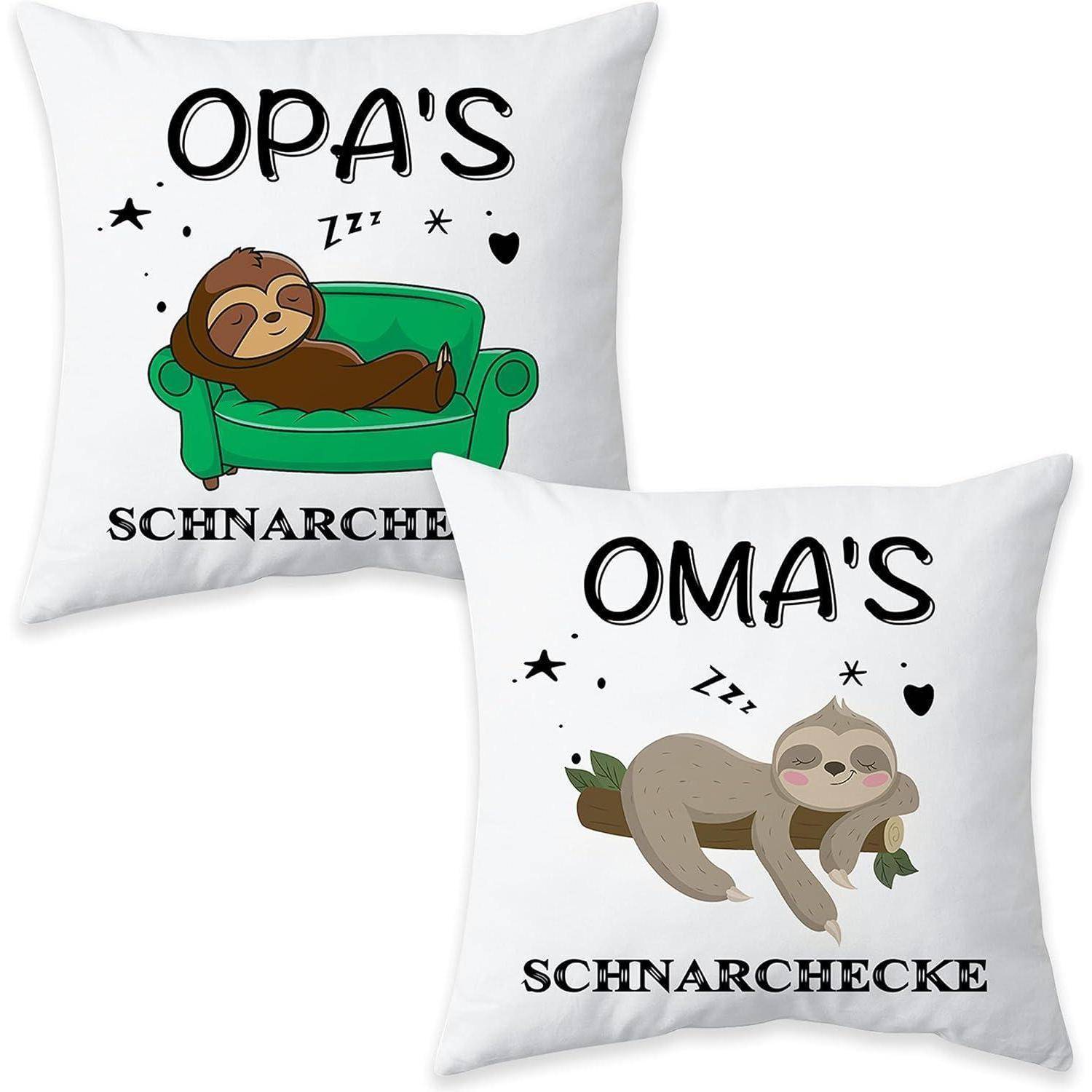 Zwei weiße Kissenbezüge, jeder mit einem Cartoon-Faultier. Der eine trägt die Aufschrift 'OPA'S SCHNARCHECKE' mit einem Faultier auf einer Couch, der andere 'OMA'S' mit einem Faultier auf Blättern.