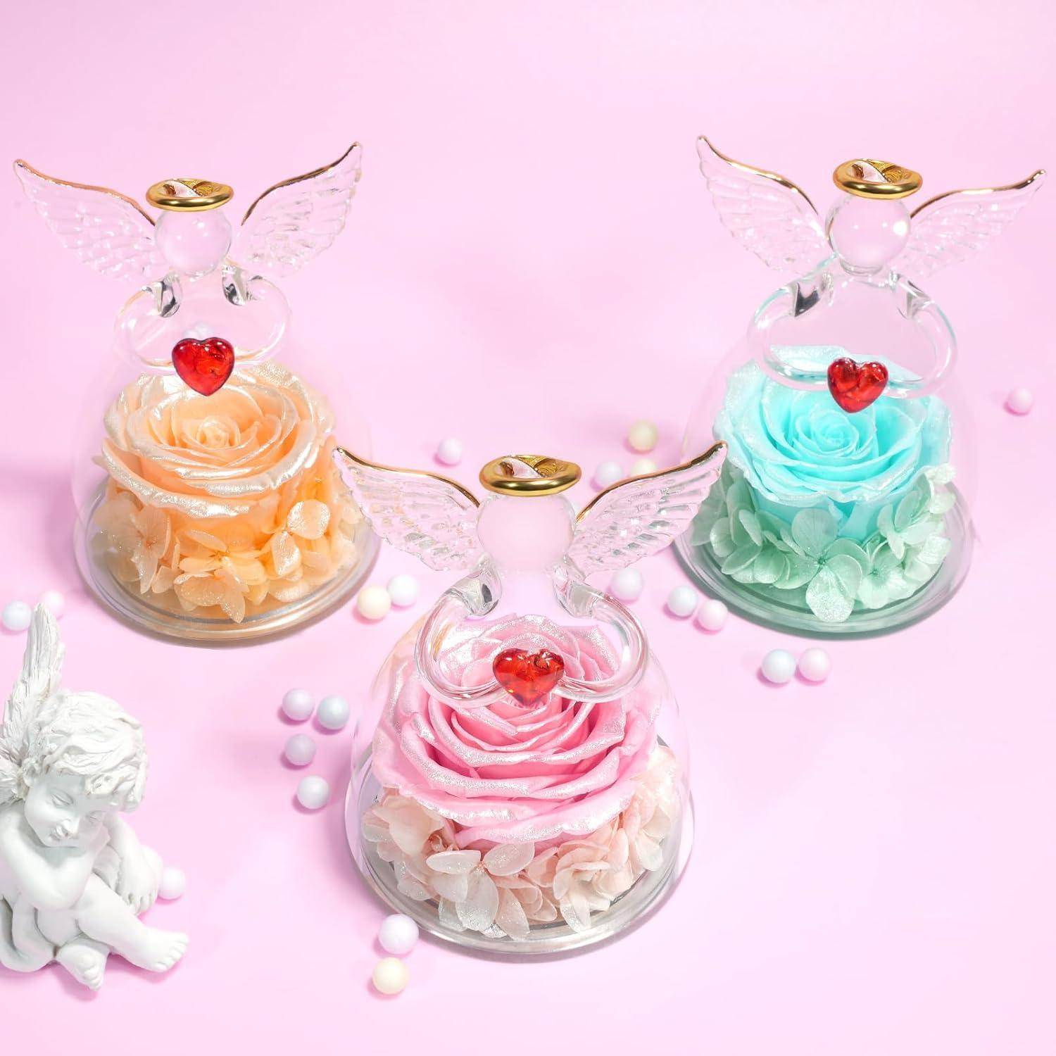 Drei Glasengelfiguren mit hohlen Zentren umschließen jeweils eine Rose in Pastellfarben: orange, rosa und blau. Jeder Engel trägt ein rotes Herz auf seiner Brust.