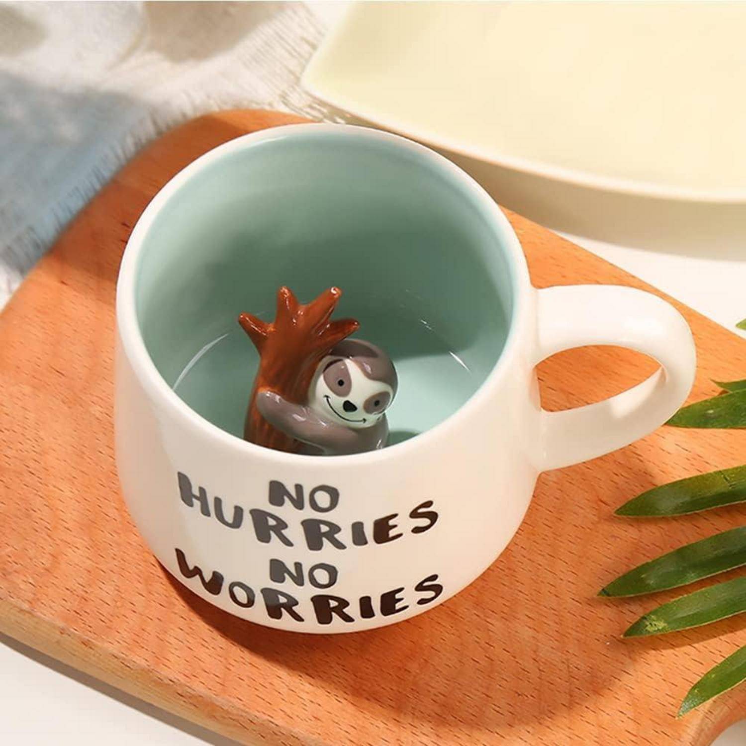 Eine weiße Tasse mit einer Faultier-Figur im Inneren und dem Text 