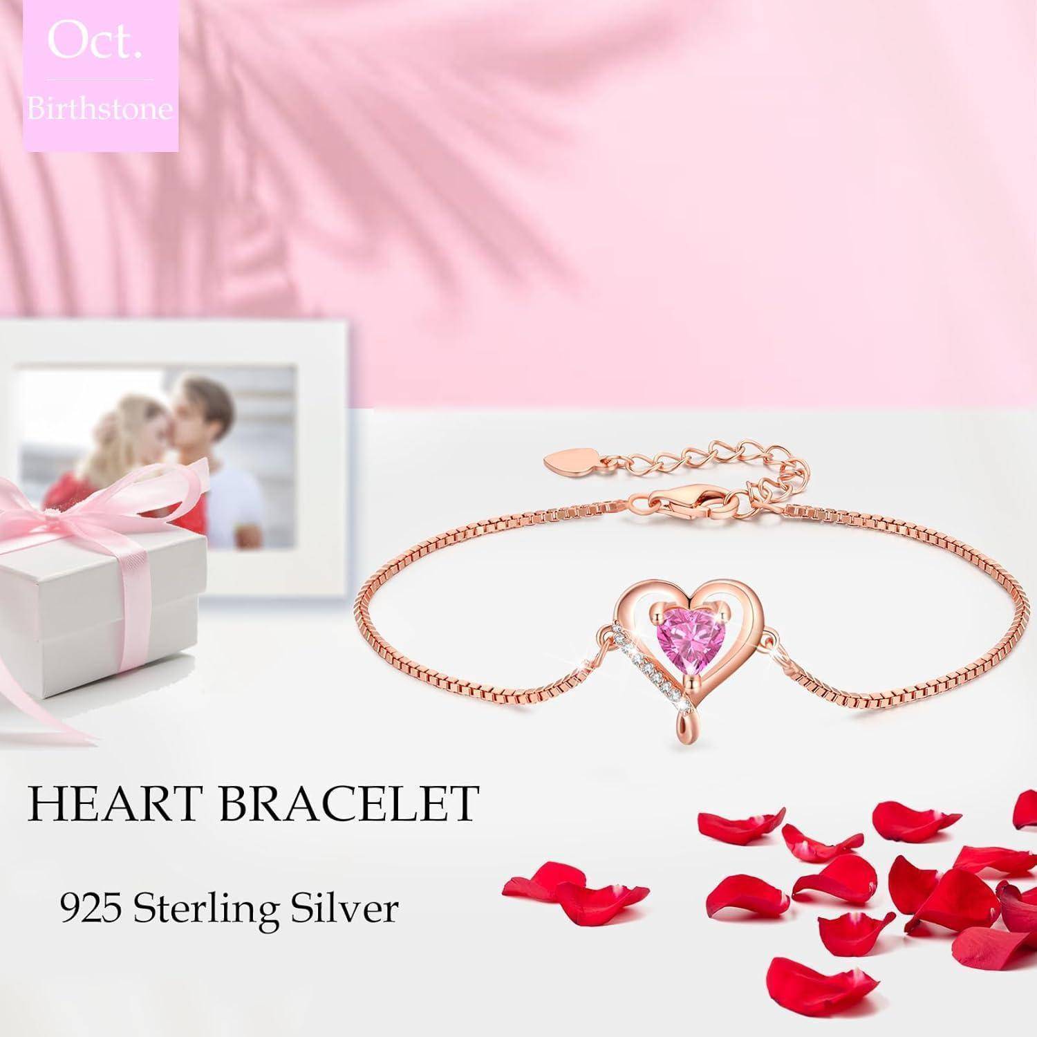 Ein rosa herzförmiges Geburtsstein-Armband aus Silber, präsentiert mit Rosenblüten, einer Geschenkbox und einem gerahmten Foto unter der Überschrift 