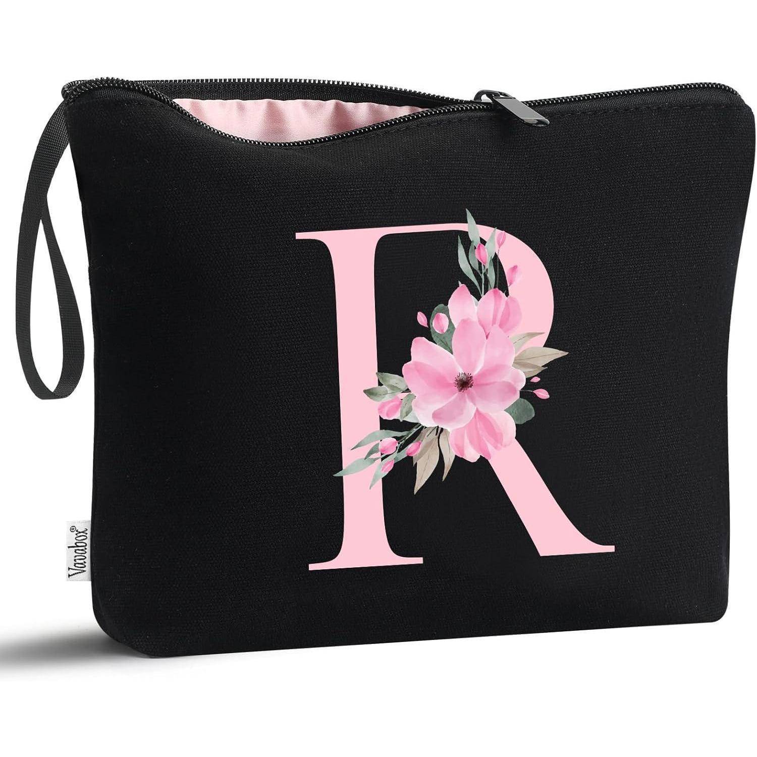 Beutel mit schwarzem Hintergrund, der einen großen rosa Buchstaben 'R' zeigt, der mit rosa Blumen verziert ist.