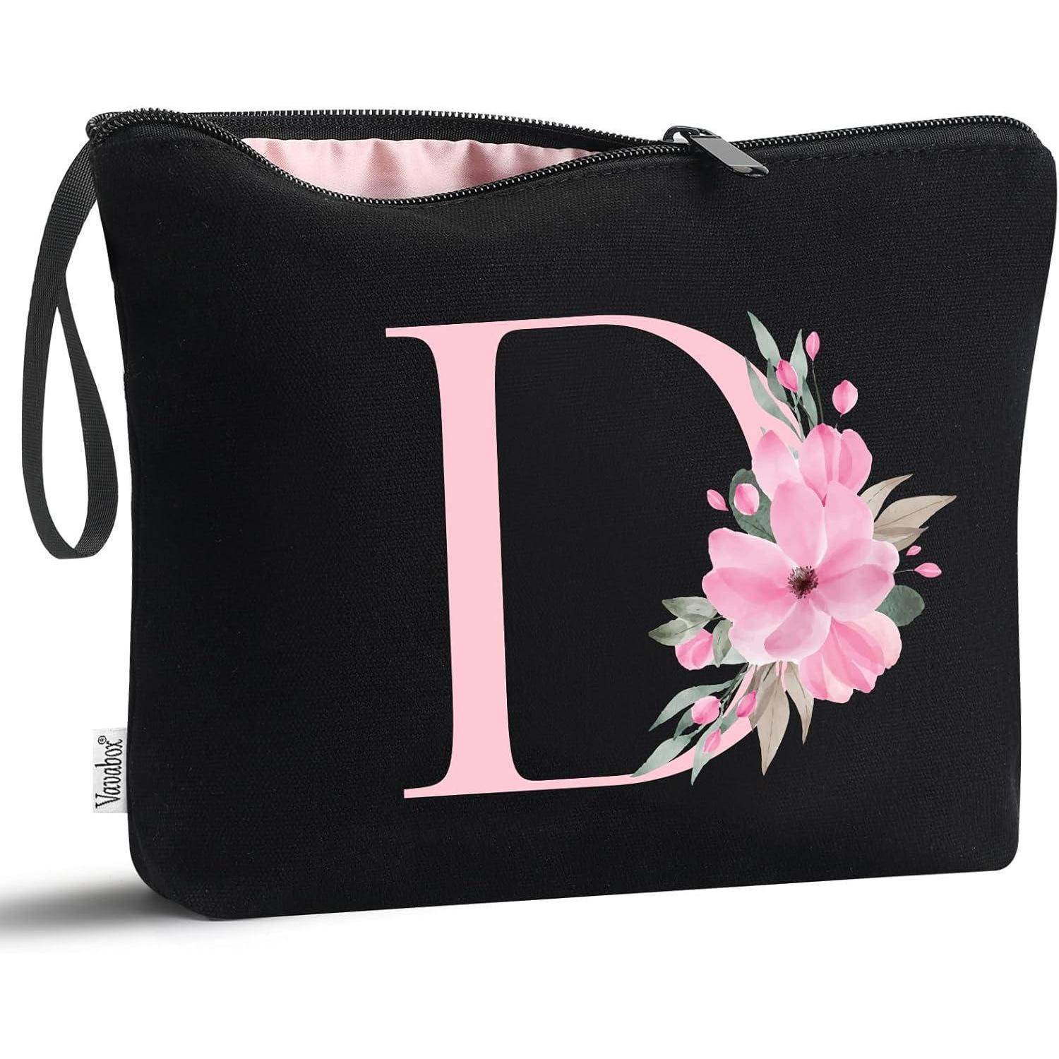 Eine schwarze Tasche mit einem rosafarbenen Blumenmuster in Form des Buchstabens 'D' auf der Vorderseite.