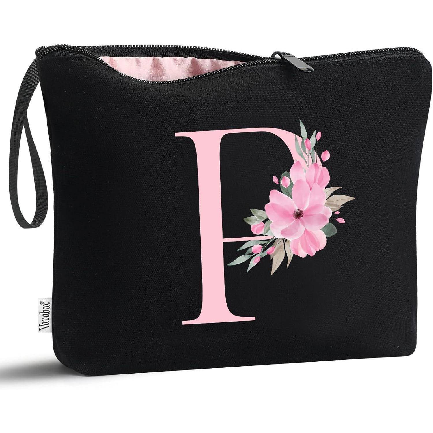 Eine schwarze Kosmetiktasche mit einem großen rosa Buchstaben 'F', der auf der Vorderseite mit rosa Blumen verziert ist.