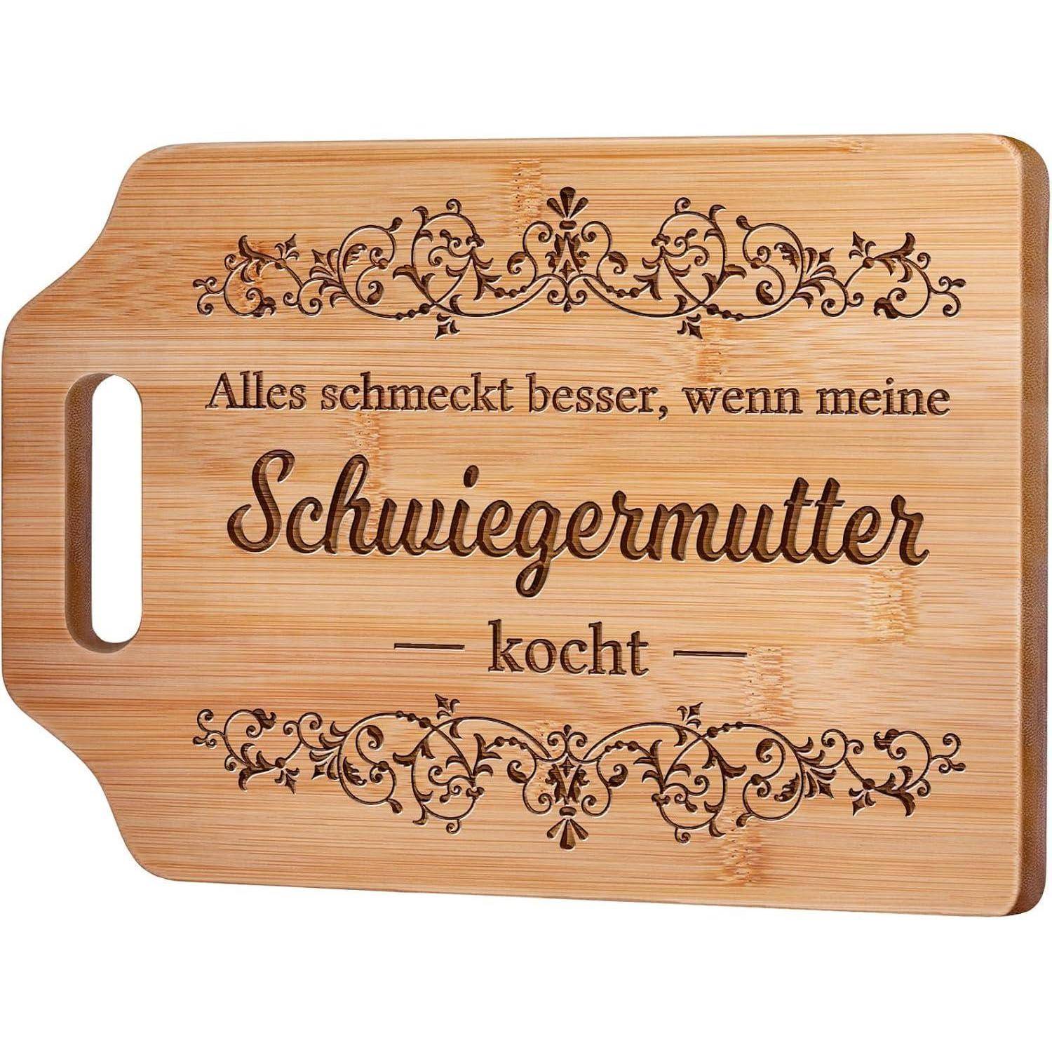 Ein Holzschneidebrett mit kunstvollen Gravuren, auf denen der deutsche Satz steht: 'Alles schmeckt besser, wenn meine Schwiegermutter kocht.
