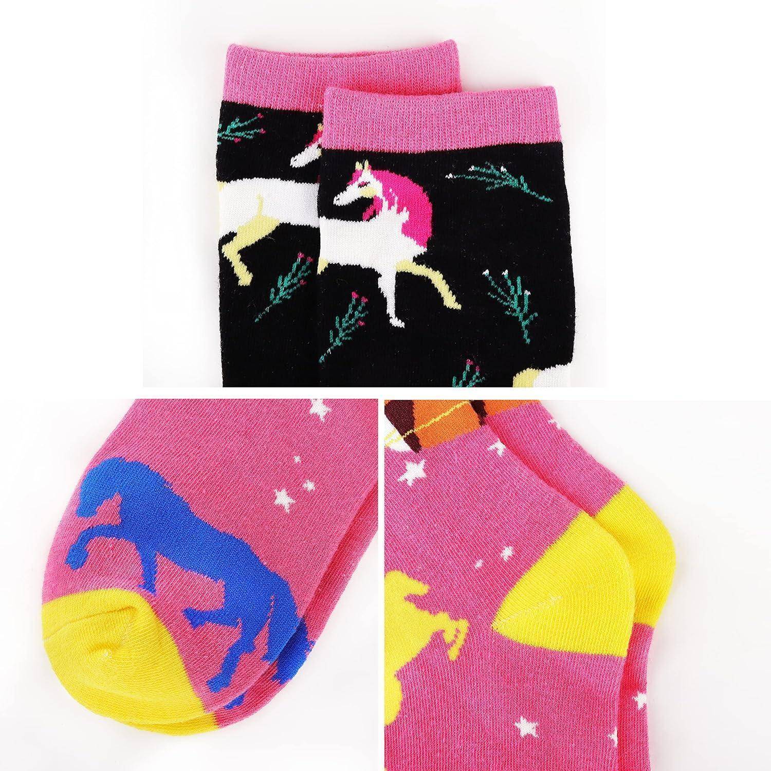 Bunte Socken mit Einhörnern in verschiedenen Posen auf einem rosa-schwarzen Hintergrund.