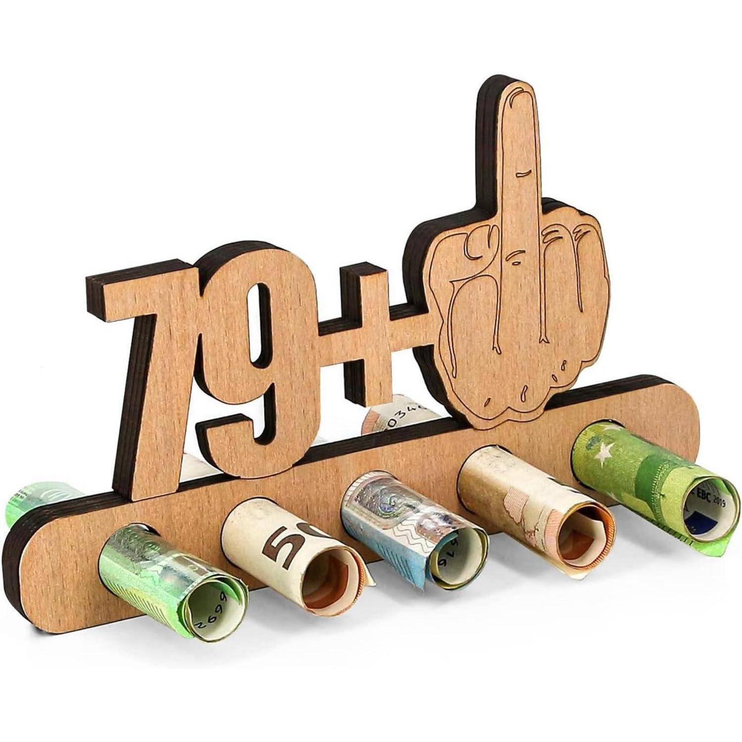 Ein Holzständer zeigt die Phrase '79+' und eine Geste, die einem ausgestreckten Mittelfinger ähnelt, während darunter zusammengerollte Geldscheine liegen.