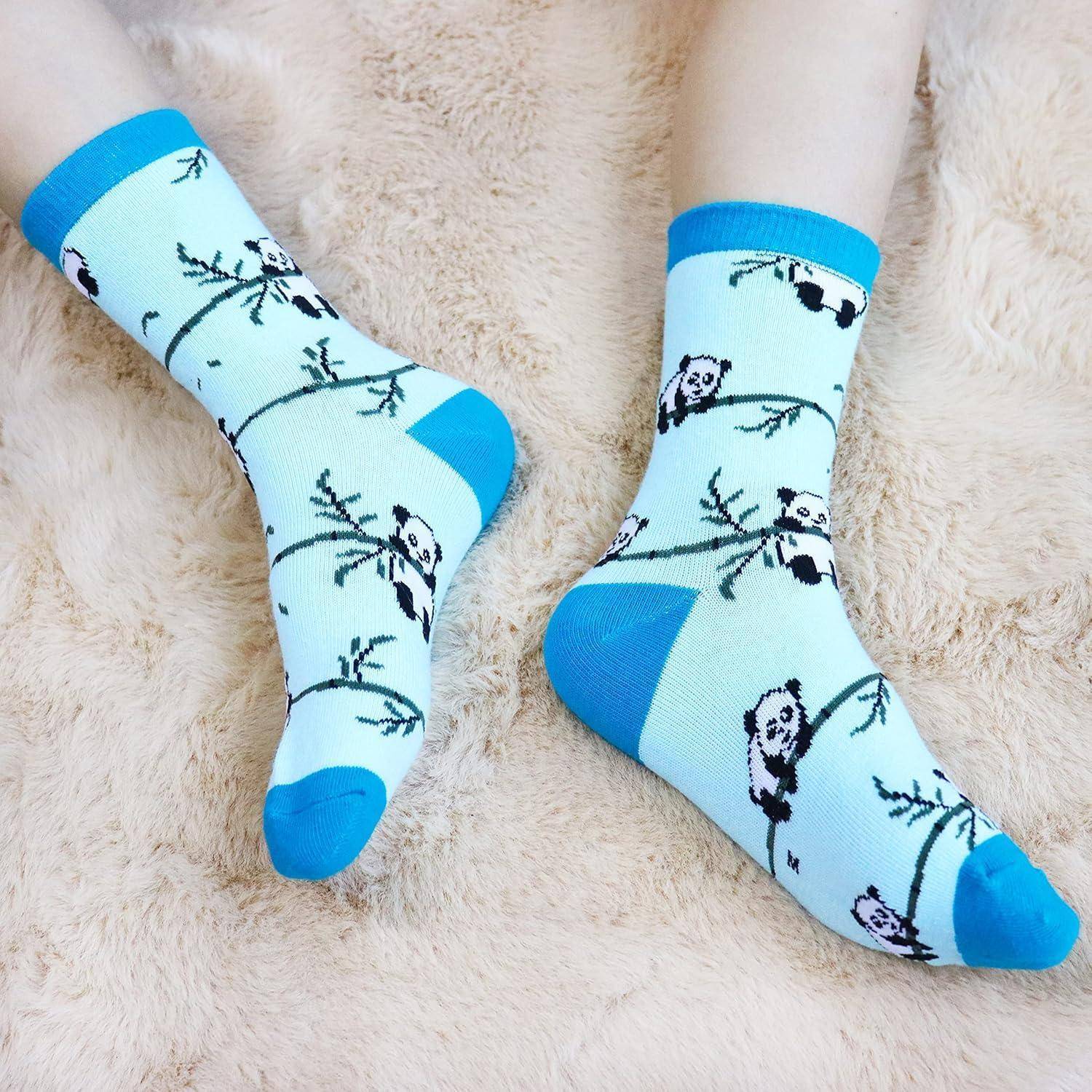 Zwei Beine, die blaue Socken mit Panda- und Bambusmustern tragen, ruhen auf einer beigen flauschigen Oberfläche.
