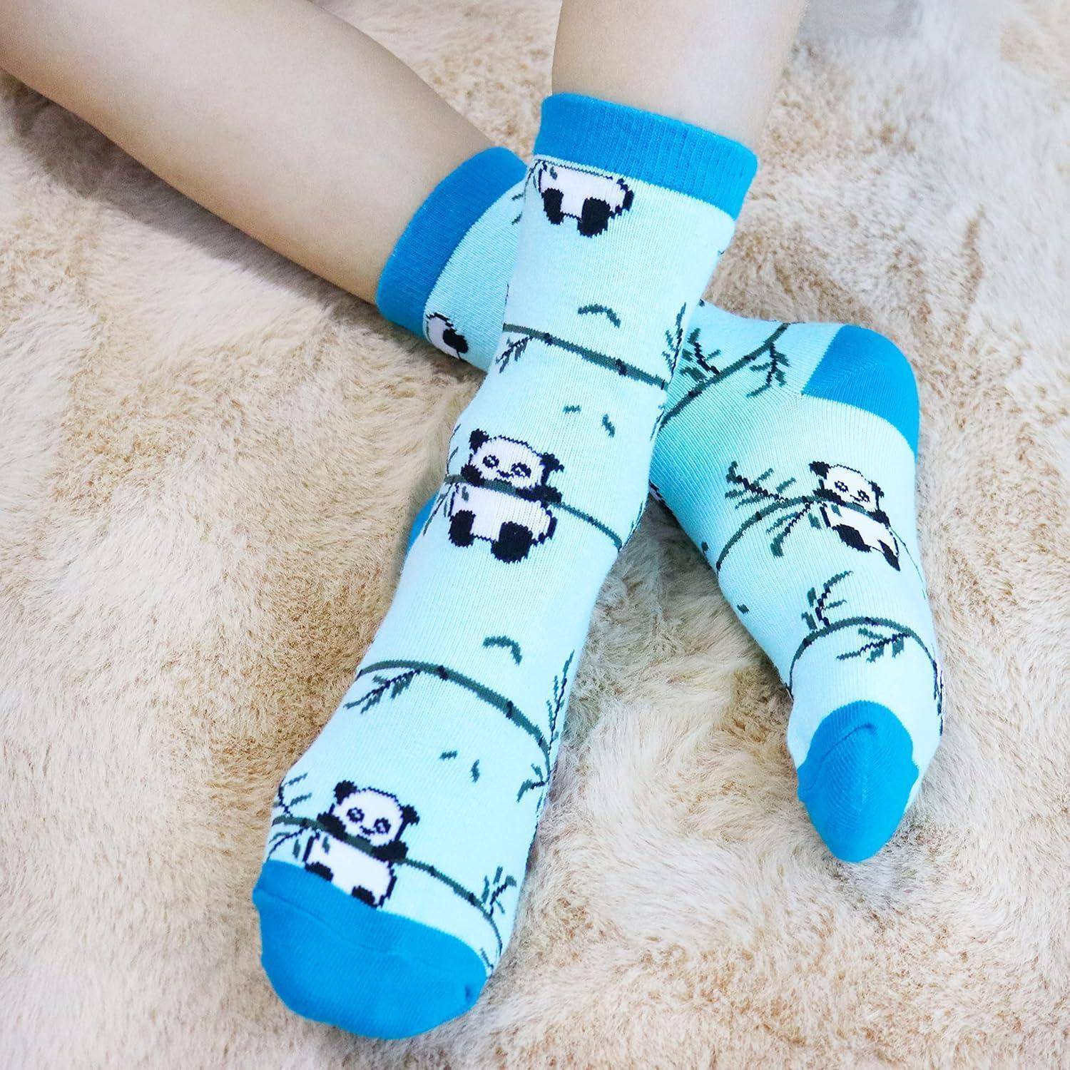 Ein Paar Füße mit hellblauen Socken, die Panda-Motive tragen, die auf einer weichen beigen Oberfläche liegen.