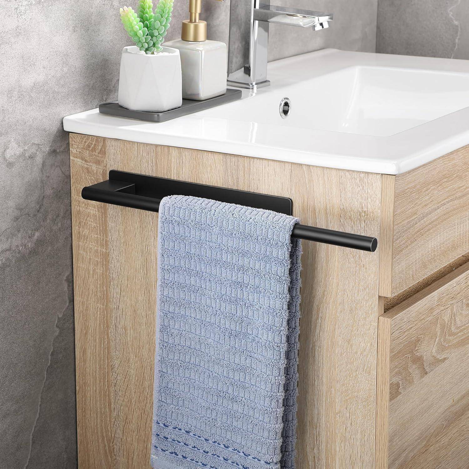 Modernes Badezimmerwaschbecken mit einem hellen Holzschrank, einem blauen Handtuch an einem schwarzen Griff, einem Wasserhahn und dekorativen Pflanzen auf der Ablage.