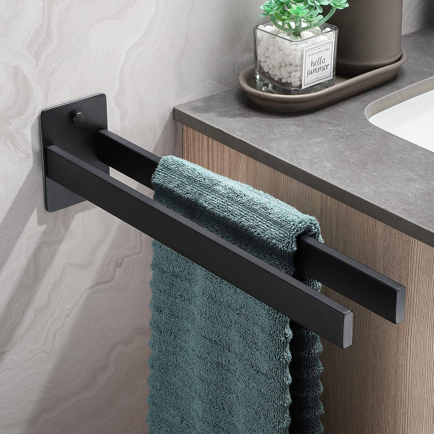 Ein Handtuchhalter im Badezimmer mit dunkler Beschichtung hält zwei petrolblaue Handtücher. Eine kleine Pflanze mit dem Etikett „hello summer