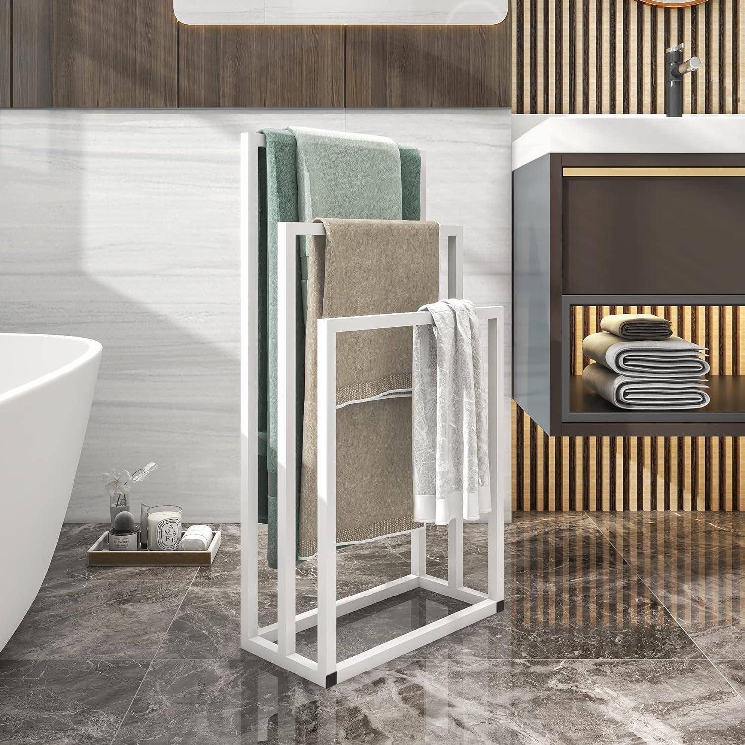 Ein modernes Badezimmer zeigt eine freistehende Badewanne, einen weißen Handtuchhalter mit Handtüchern und ein wandmontiertes Waschbecken mit Regalen. Der Boden ist gefliest.