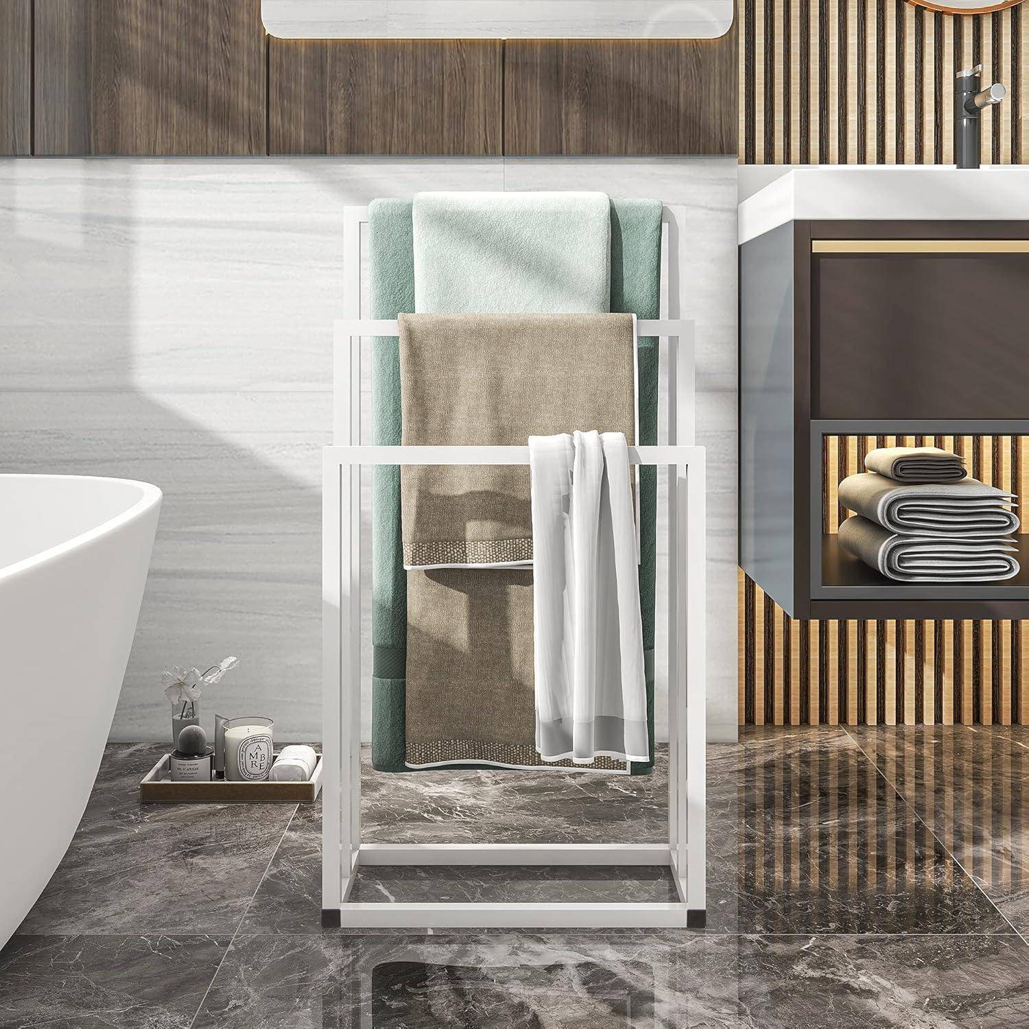 Modernes Badezimmer mit einer weißen freistehenden Badewanne, einem Handtuchhalter aus Metall mit zusammengelegten Handtüchern und einem Waschbecken mit Regalen, vor einer Wand aus Holz und Fliesen.