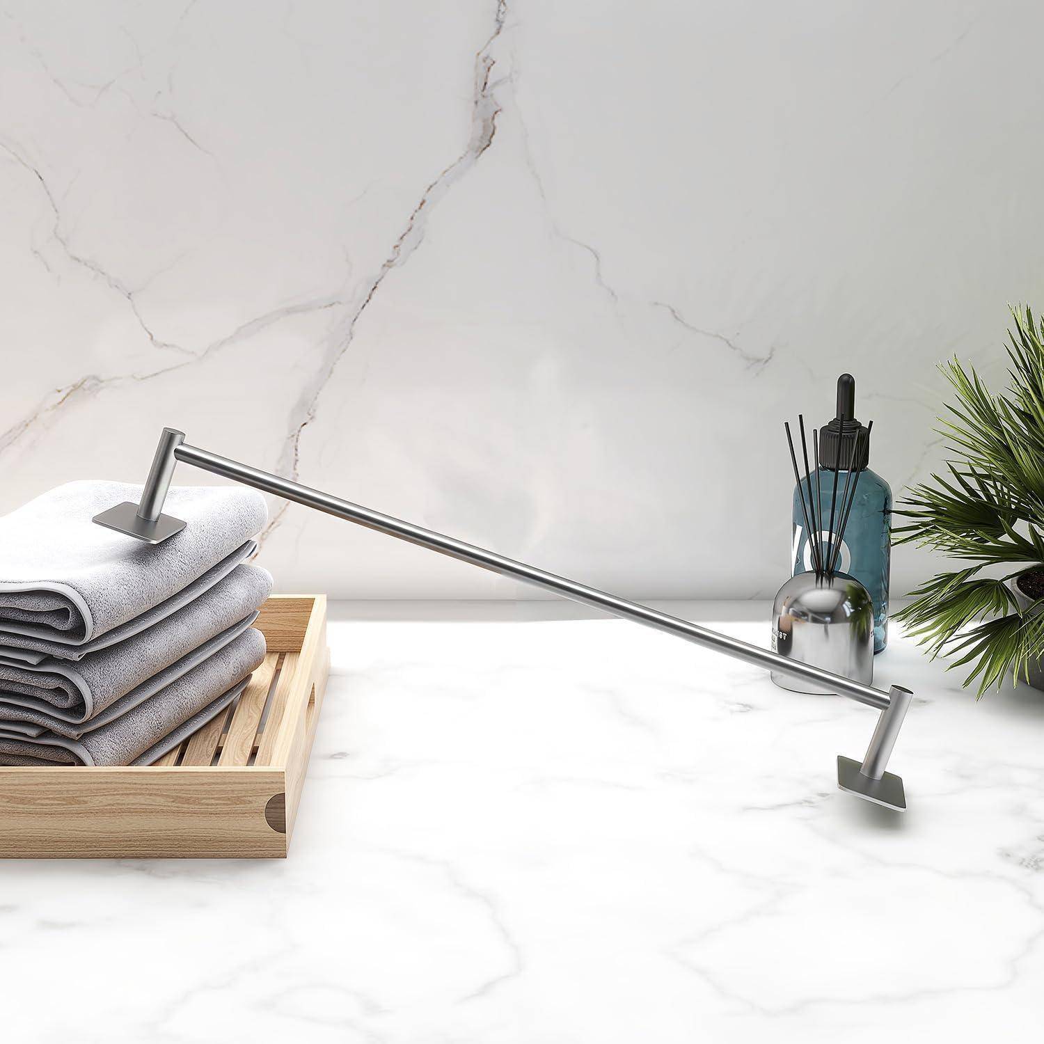 Eine moderne Badezimmerablage mit Marmorfinish zeigt gestapelte graue Handtücher auf einem Holztablett, einen eleganten silbernen Wasserhahn und dekorative Pflanzen.