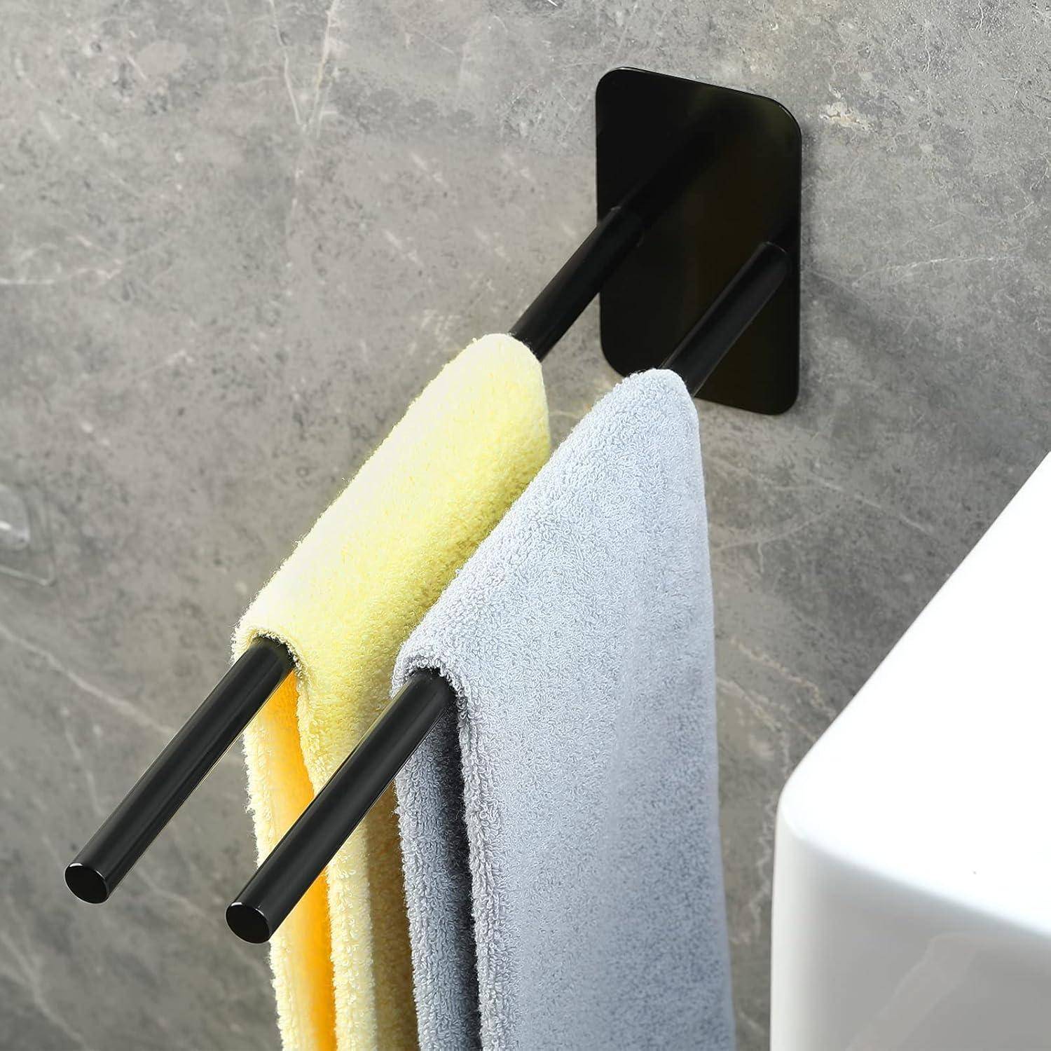 Eine Badezimmerwand mit zwei Handtüchern, eines gelb und eines grau, die an einer eleganten schwarzen Stange neben einer weißen Arbeitsplatte hängen.