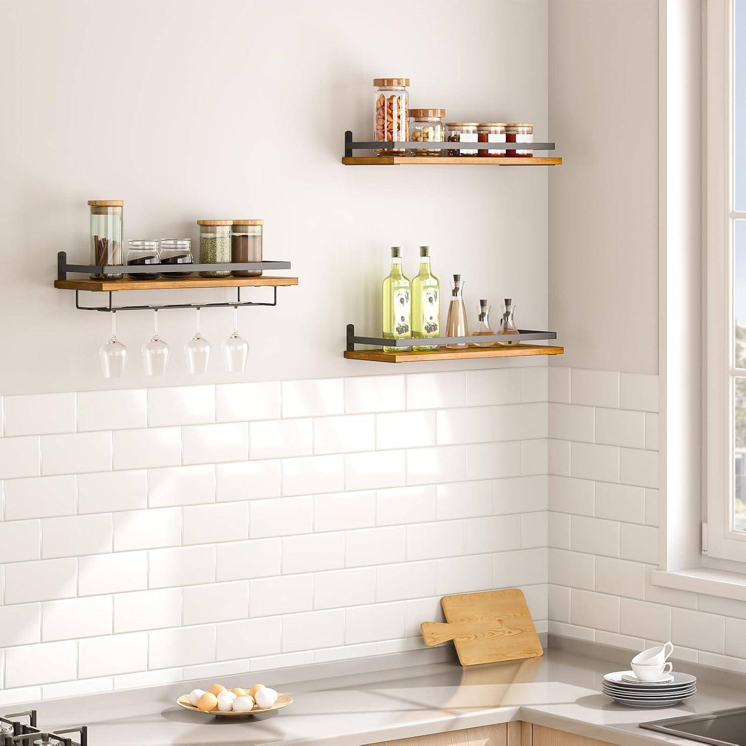 Moderne Küche mit weißen Fließen, drei Holzregalen mit Gläsern und Flaschen, Weingläsern, die darunter hängen. Helles Fensterlicht.