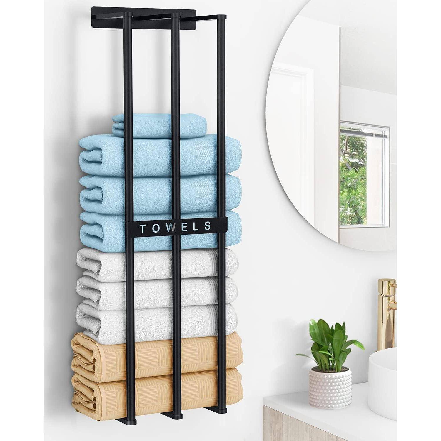 An der Wand hängt ein Gestell mit sorgfältig gefalteten blauen, weißen und beigen Handtüchern, versehen mit einem Schild mit der Aufschrift „Handtücher