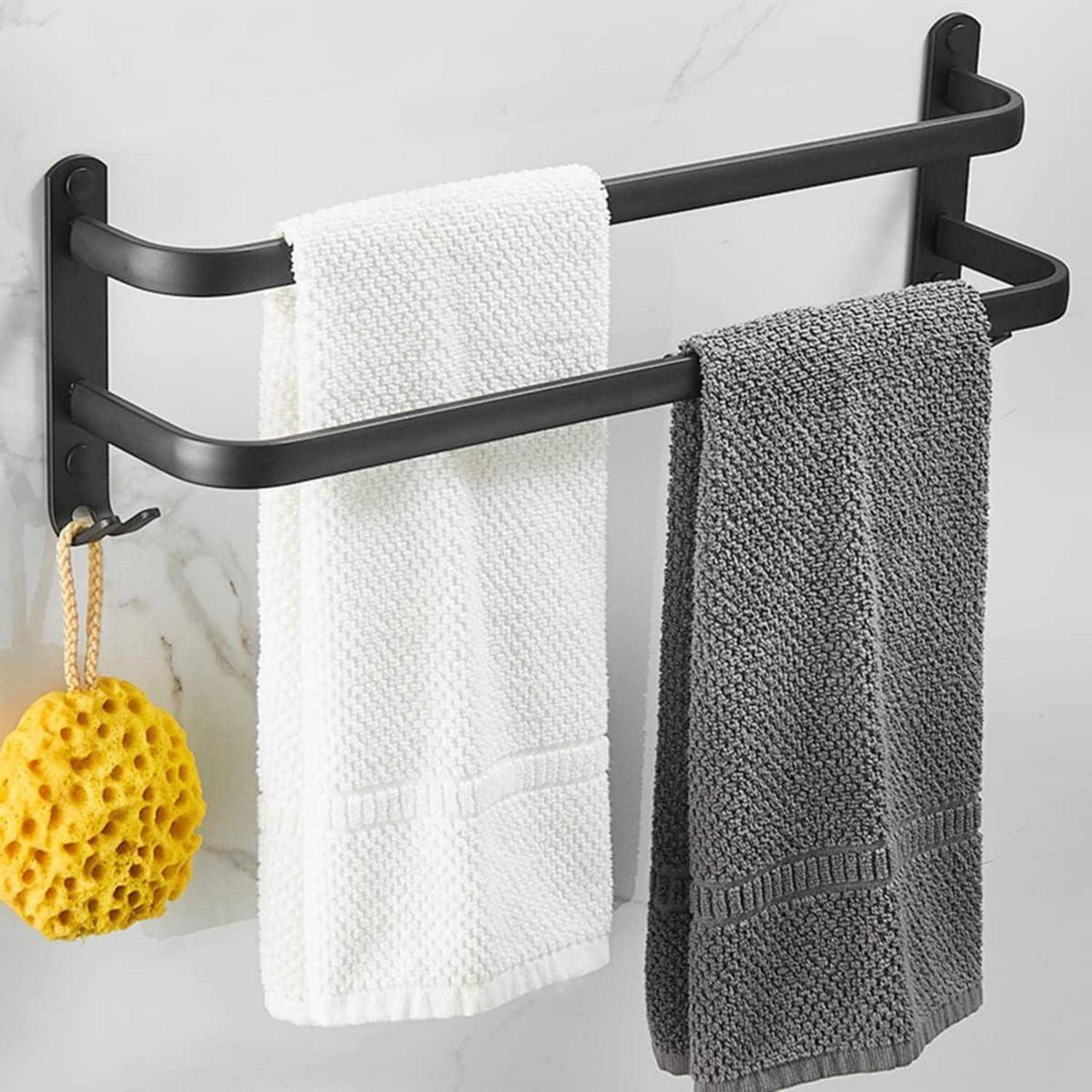 Ein Handtuchhalter im Badezimmer trägt ein weißes Handtuch, ein graues Handtuch und einen gelben Schwamm vor einer Marmorwand.