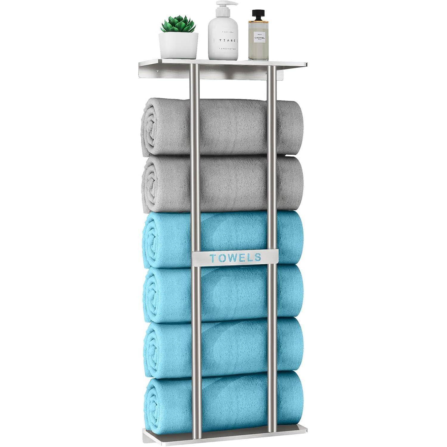 Ein wandmontiertes Handtuchgestell mit sechs aufgerollten Handtüchern, drei graue und drei blaue, mit einer kleinen Pflanze und einer Seifenflasche auf dem oberen Regal.