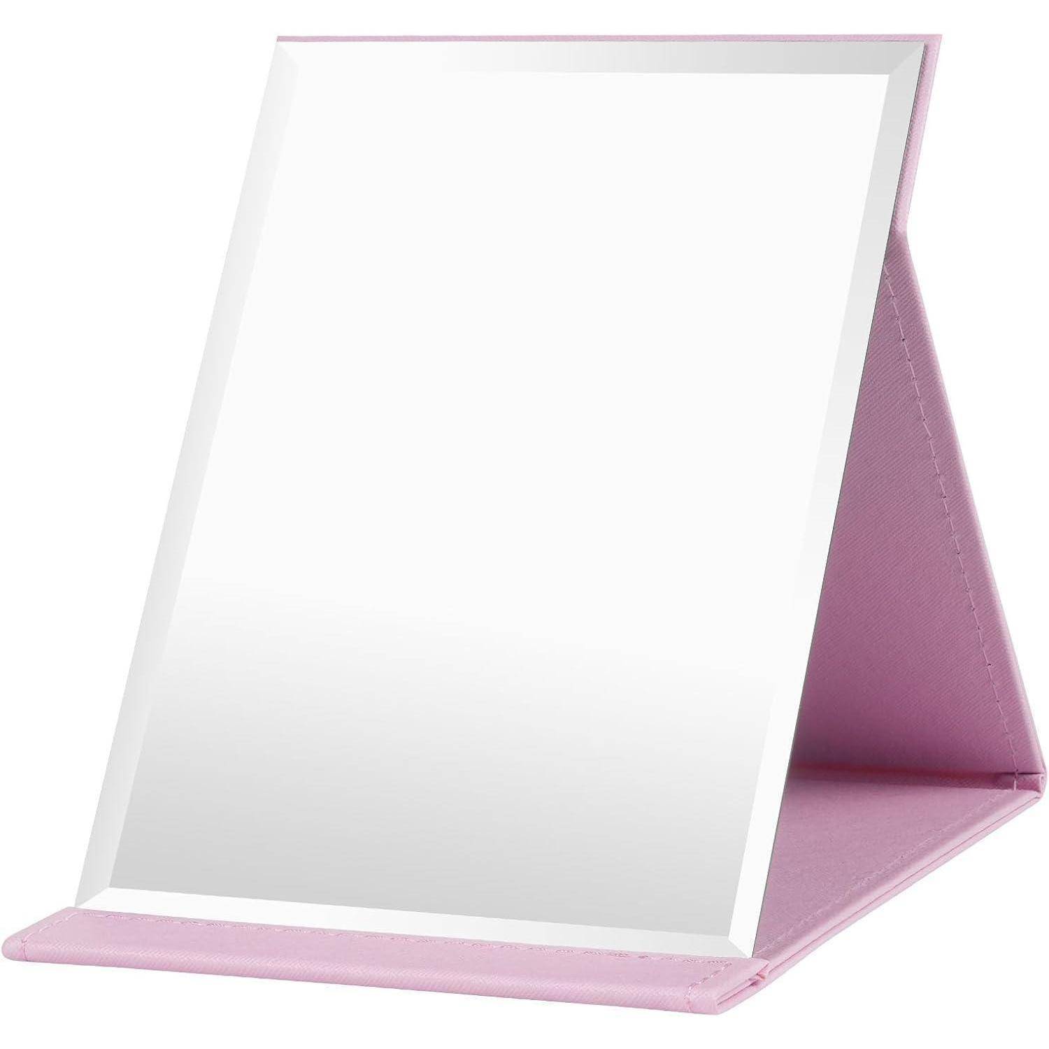 Ein tragbarer Tischspiegel mit einem rosa zusammenklappbaren Ständer, der das Licht auf seiner Oberfläche reflektiert.