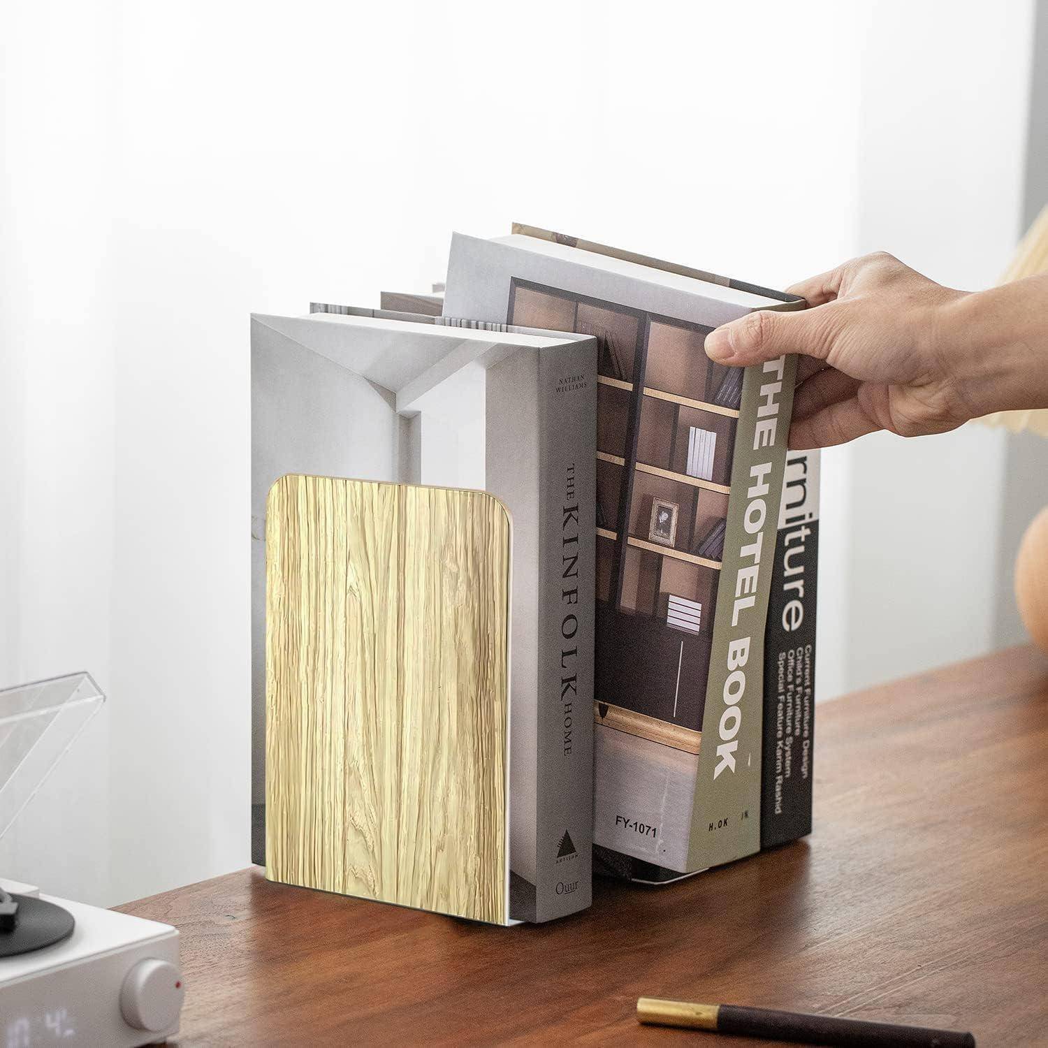 Eine Person ordnet Bücher an, die aufrecht auf einer Holzoberfläche stehen. Die Bücher haben Einbände in neutralen Farben, wobei eines eine strukturierte Oberfläche aufweist.