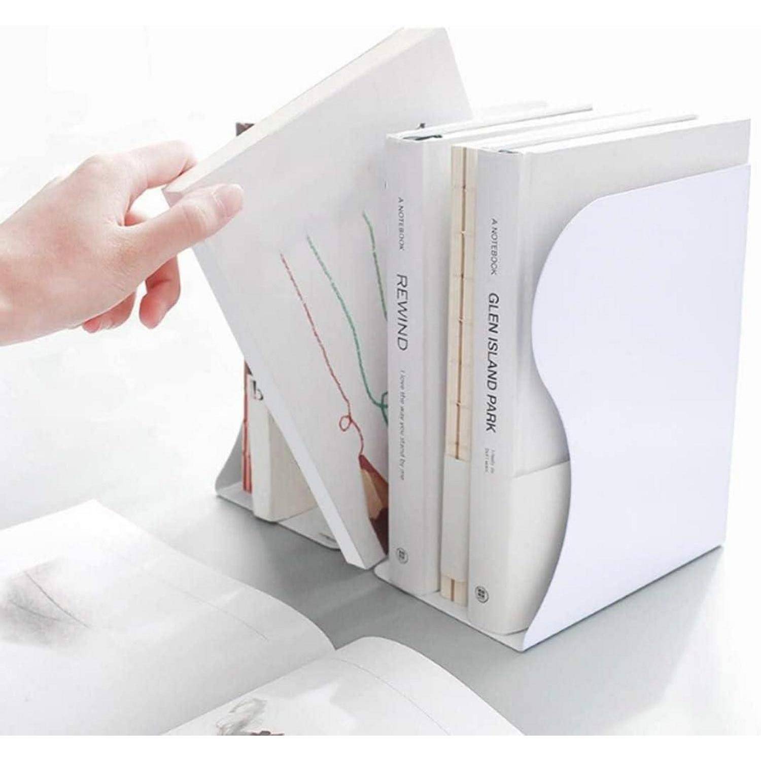 Eine Hand platziert ein Buch zwischen weißen Büchern, die von einem modernen, minimalistischen Buchstützer aufrecht gehalten werden, auf einer weißen Oberfläche.