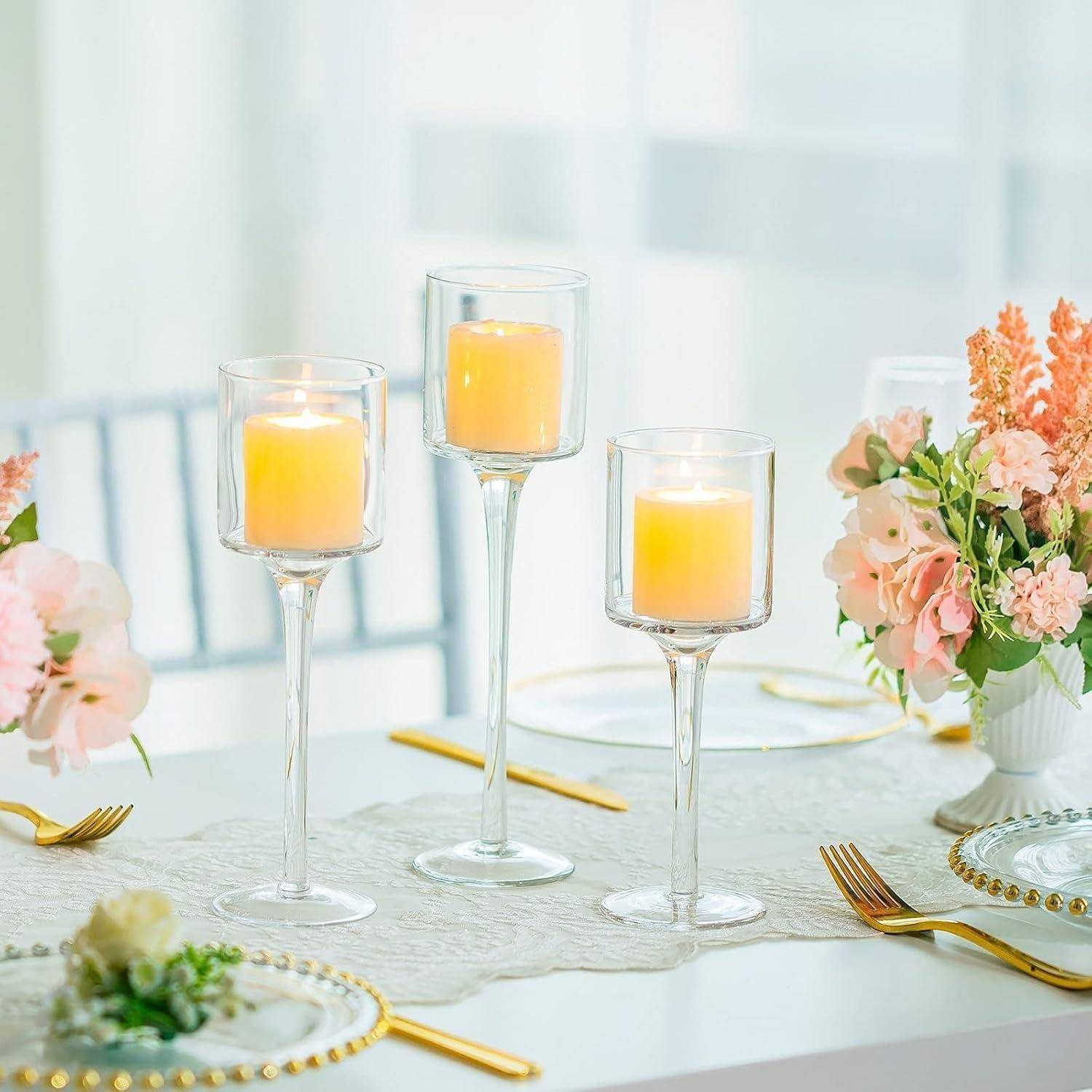 Elegante Tischdecke mit drei brennenden Kerzen in Glashaltern und einer Blumenarrangement aus rosa und weißen Blumen auf einer weißen Tischdecke.