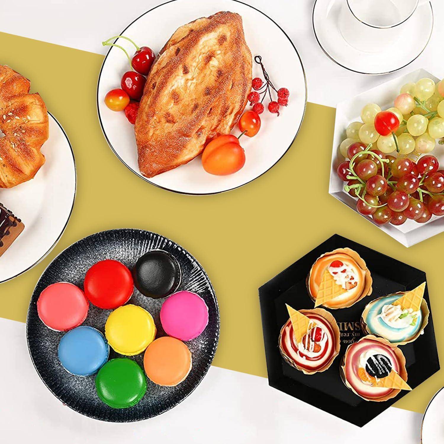 Luftaufnahme verschiedener Desserts und Snacks auf einem Tisch, darunter Gebäck, bunte Macarons, Trauben und dekorierte Cupcakes.