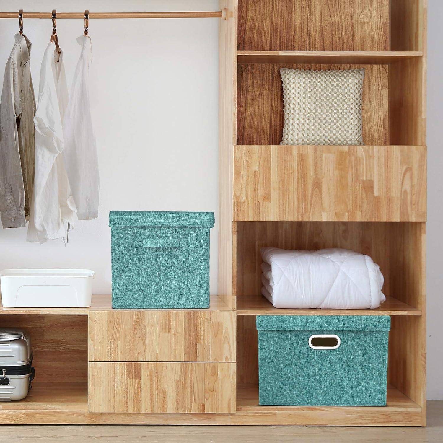 Holzschrank mit hängenden Kleidungsstücken, türkisfarbenen Aufbewahrungsboxen, einem gewebten Kissen, einer ordentlich zusammengefalteten weißen Decke und einem Koffer am unteren Ende.