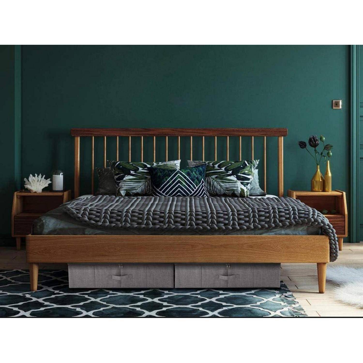 Ein Schlafzimmer mit einem Holzbettgestell, grüner und grauer Bettwäsche, grüner Wand, zwei Nachttischen und dekorativen Kissen, die eine gemütliche Atmosphäre schaffen.