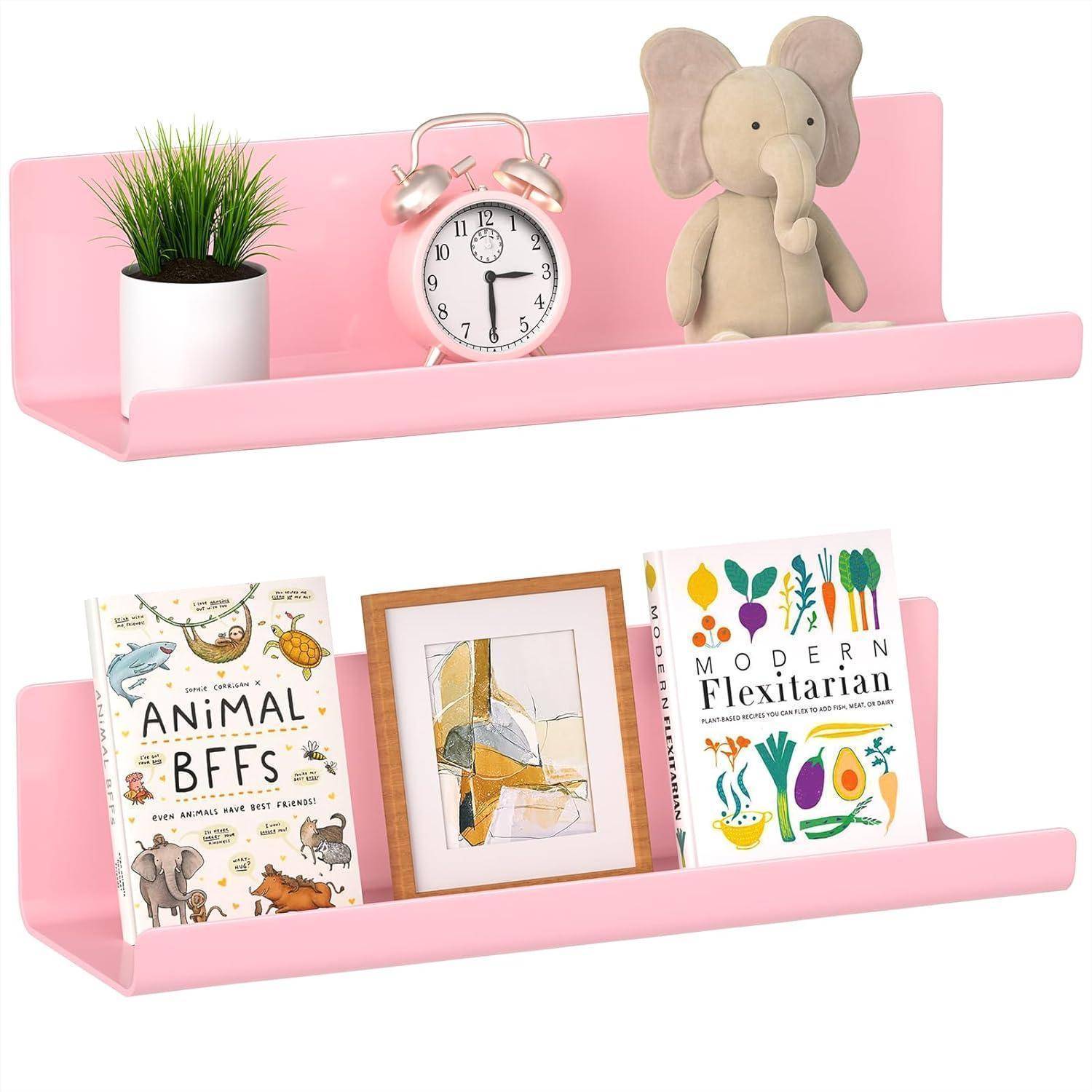 Ein rosa Wandregal mit einer Uhr, einer Pflanze und einem Stoffelefanten oben drauf. Darunter sind Bücher und ein gerahmtes Bild ordentlich angeordnet.